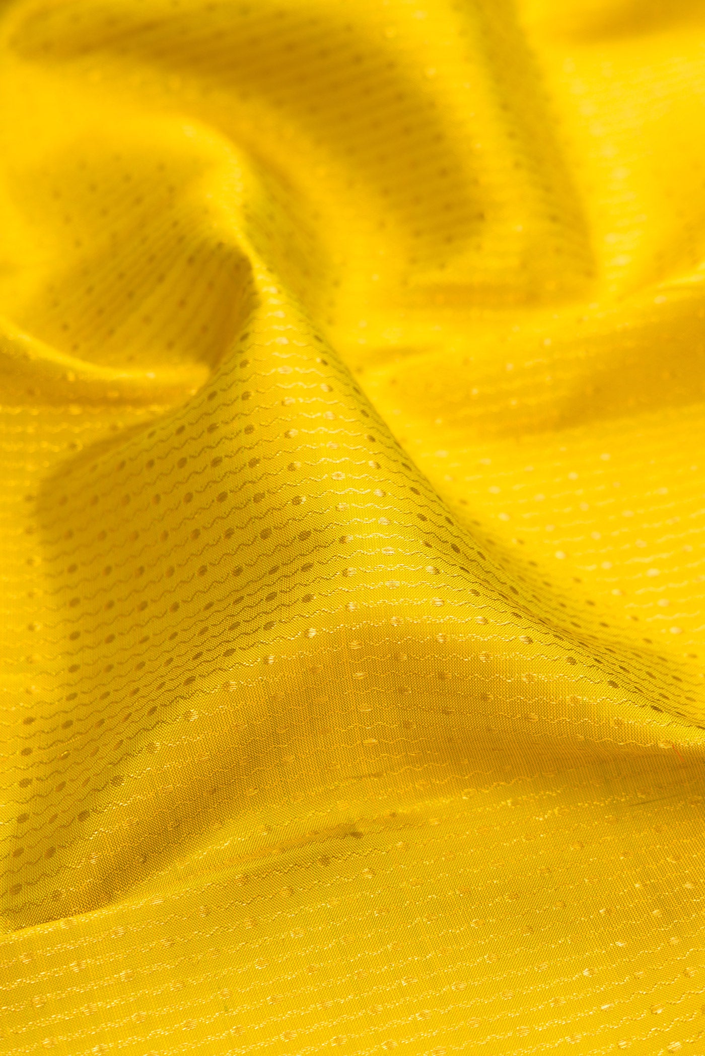 Close up of Yellow Kanchipuram Silk Saree with Zari Butta on the body and Fancy Border.  displaying folds