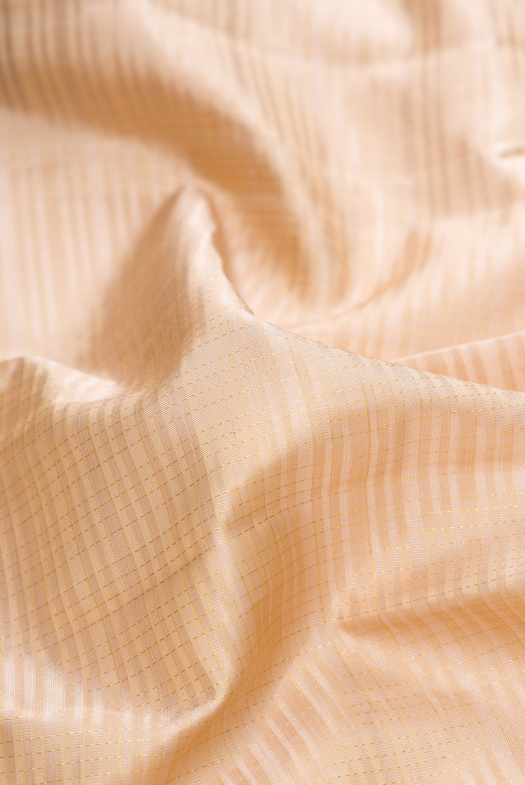 Close up of Pure Silk Beige Kanchipuram Saree with Checked design on the body and Zari Border.  displaying folds