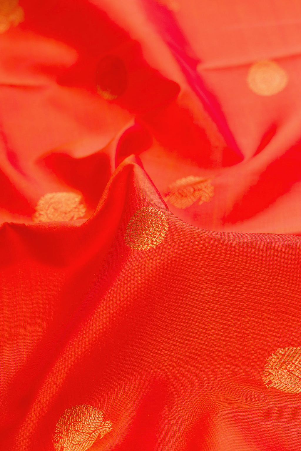 Close up of Pure Silk Pure Zari Brick Orange Dual Tone Kanchipuram Saree with Zari Butta on the body and Zari Border.  displaying folds
