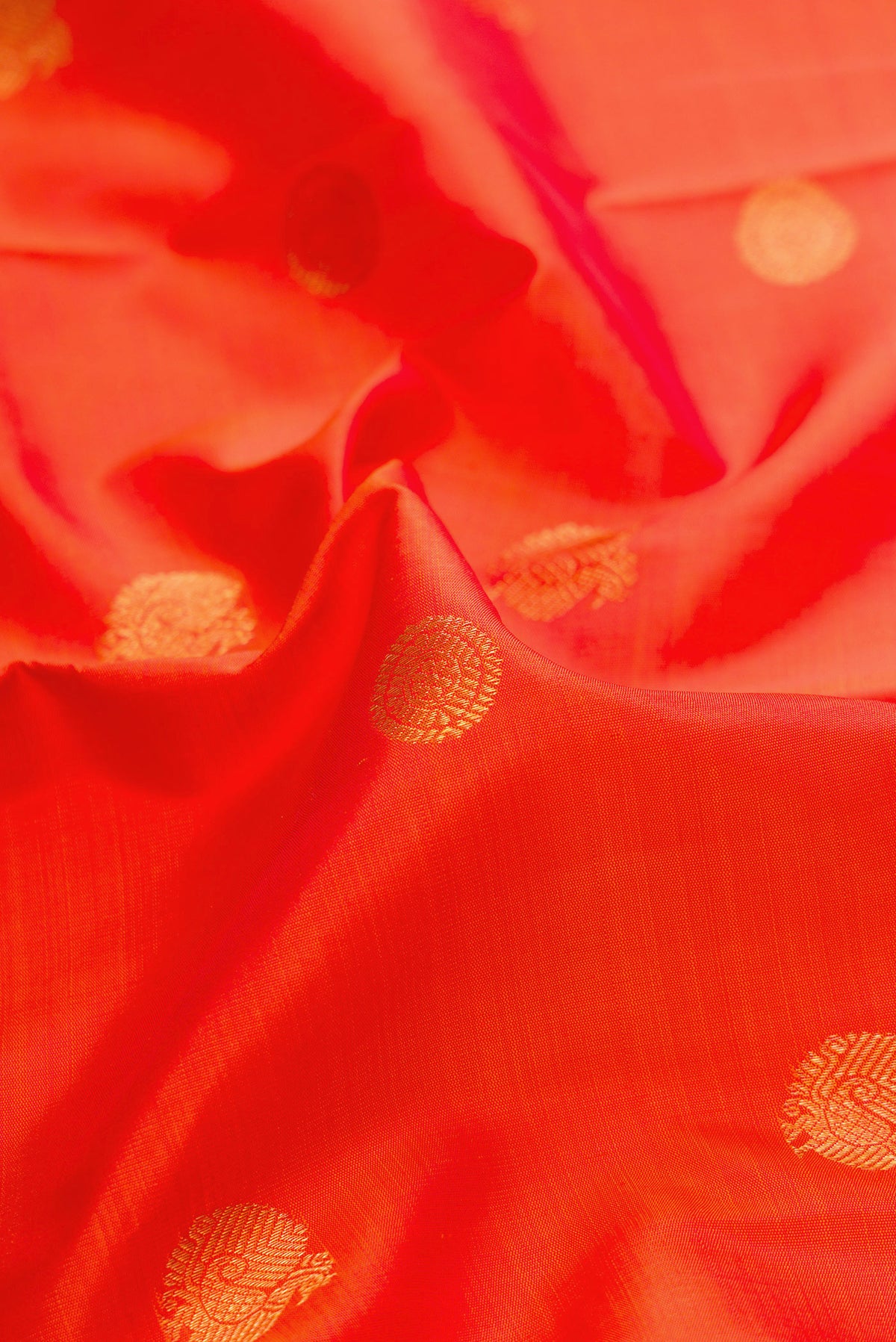 Close up of Pure Silk Pure Zari Brick Orange Dual Tone Kanchipuram Saree with Zari Butta on the body and Zari Border.  displaying folds