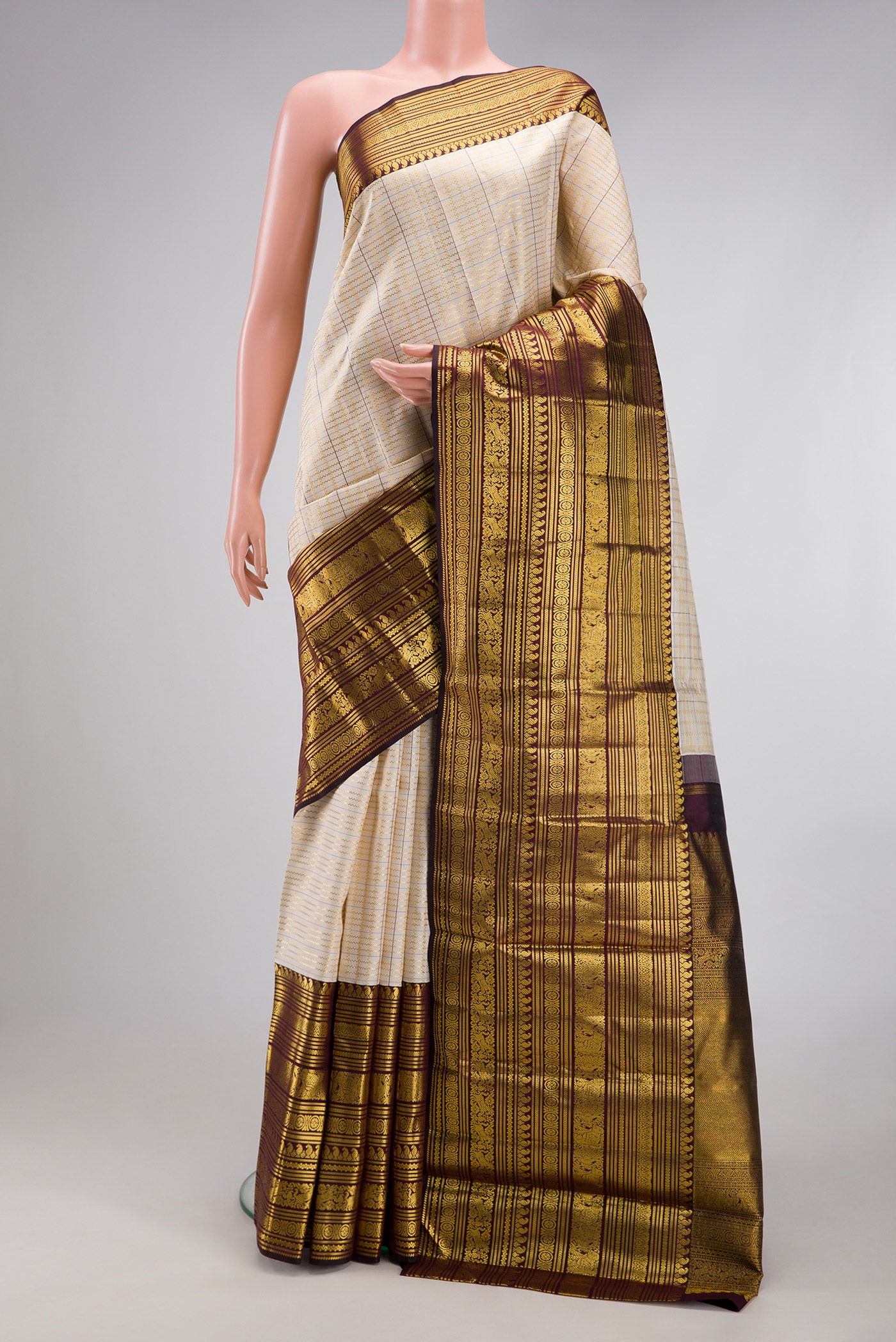 Cream Kanchipuram Silk Saree with Checked design on the body and Zari Border.  displayed on a mannequin