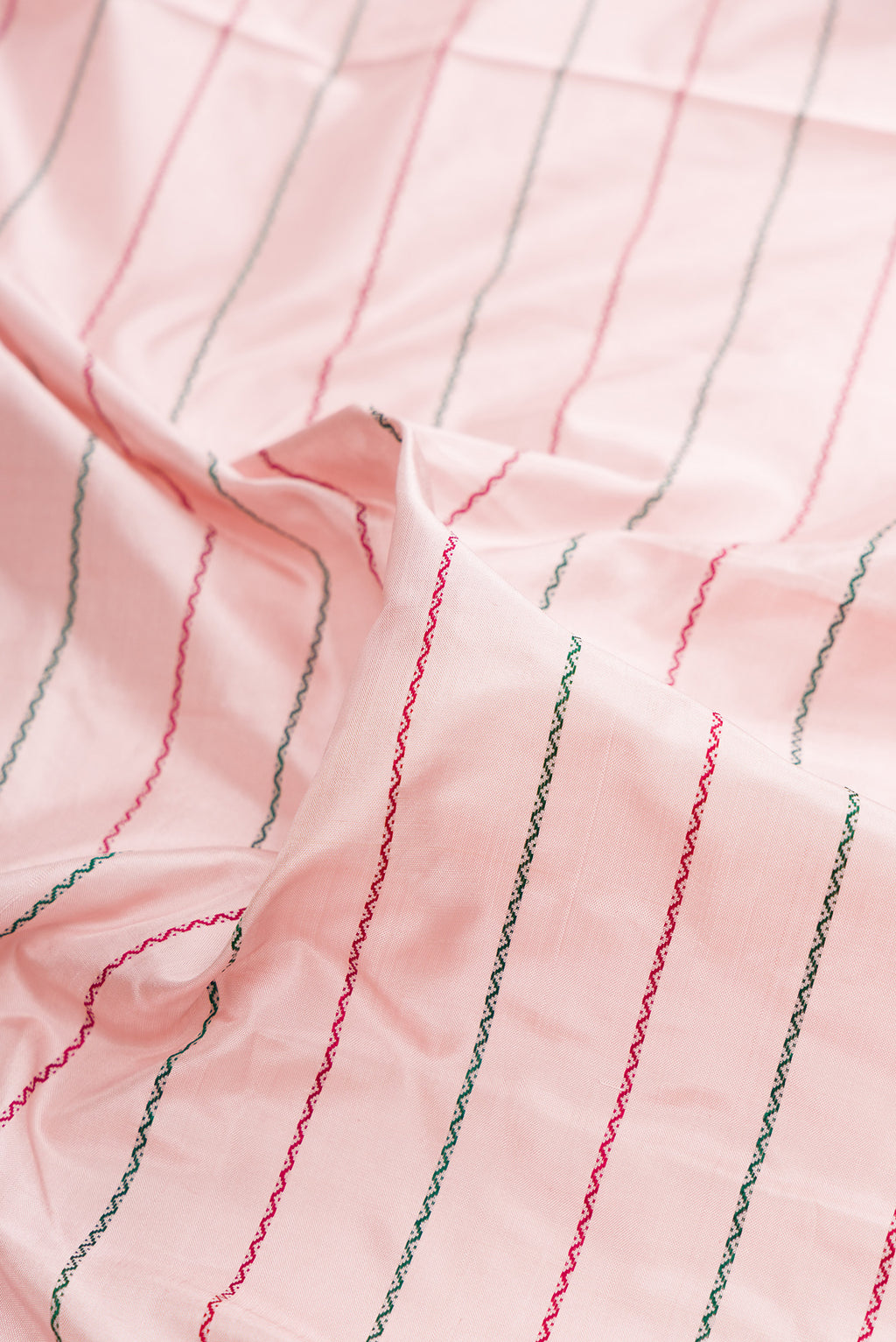 Close up of Pure Silk Rose pink Kanjivaram Saree with Veldhari on the body and Zari Border.  displaying folds