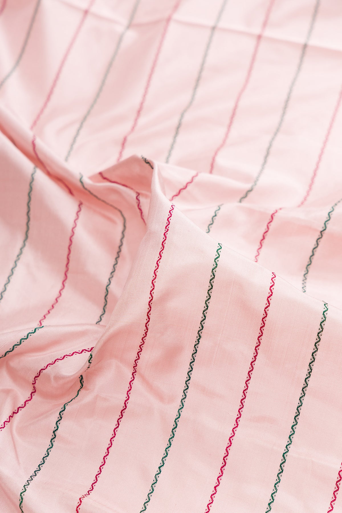 Close up of Pure Silk Rose pink Kanjivaram Saree with Veldhari on the body and Zari Border.  displaying folds