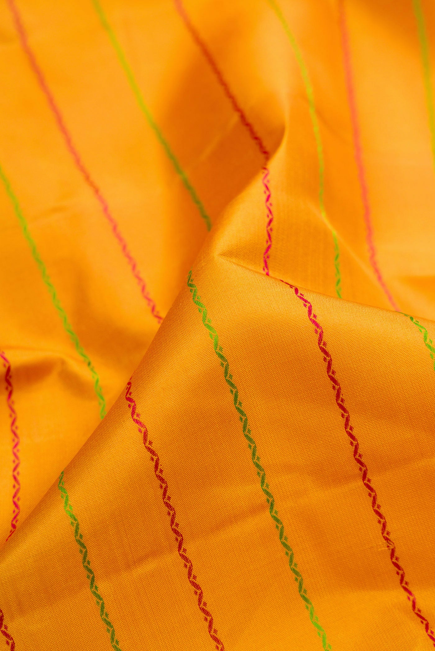Close up of Mustard Kanjivaram Silk Saree with Veldhari on the body and Thread Border.  displaying folds