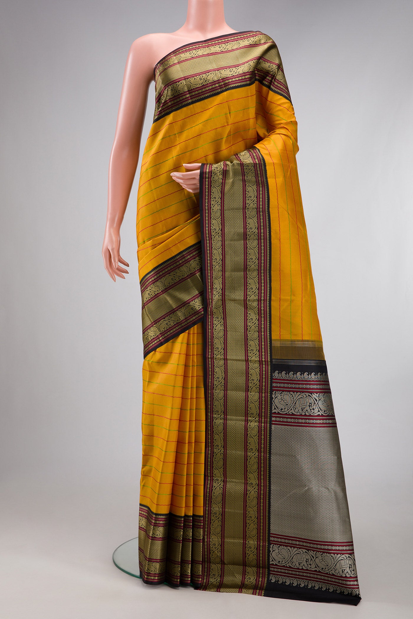 Mustard Kanjivaram Silk Saree with Veldhari on the body and Thread Border.  displayed on a mannequin