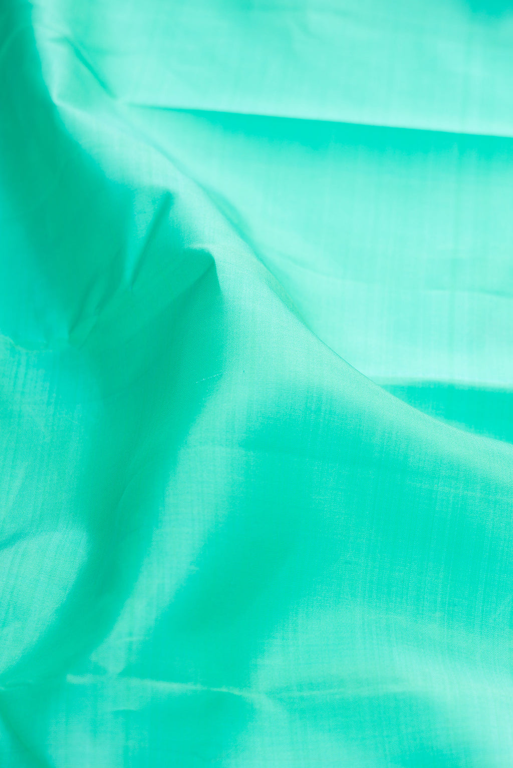 Close up of Pure Silk Sea Green Kanjivaram Saree with Plain Body and Zari Border.  displaying folds