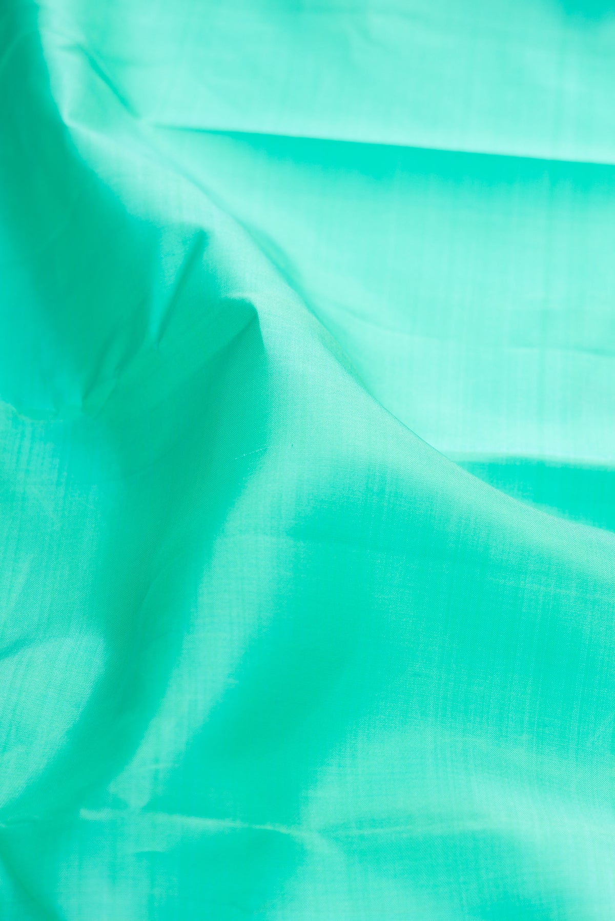 Close up of Pure Silk Sea Green Kanjivaram Saree with Plain Body and Zari Border.  displaying folds