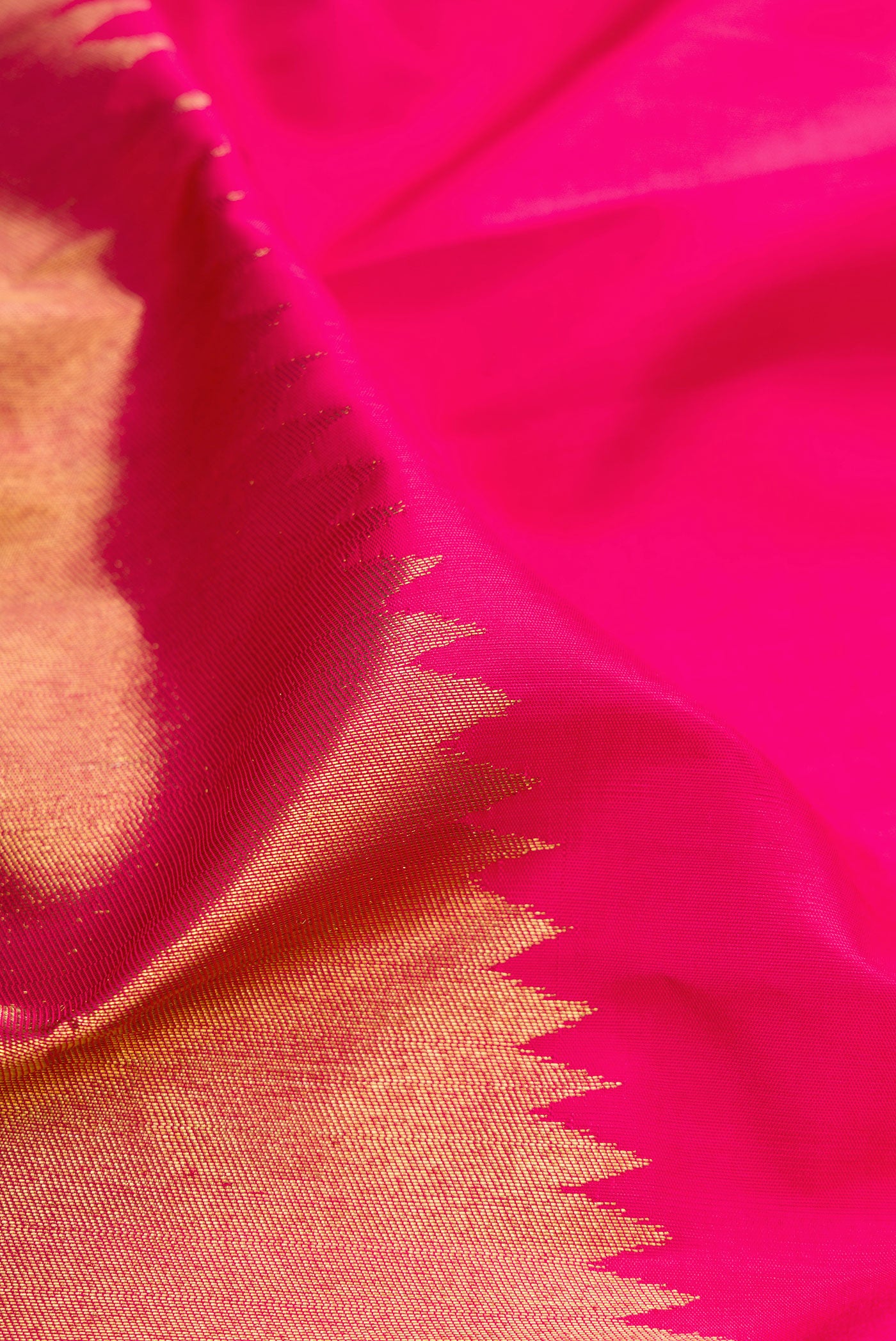 Close up of Pure Silk Pure Zari Pink Kanjivaram Saree with Plain Body and Rising Temple Border.  displaying folds