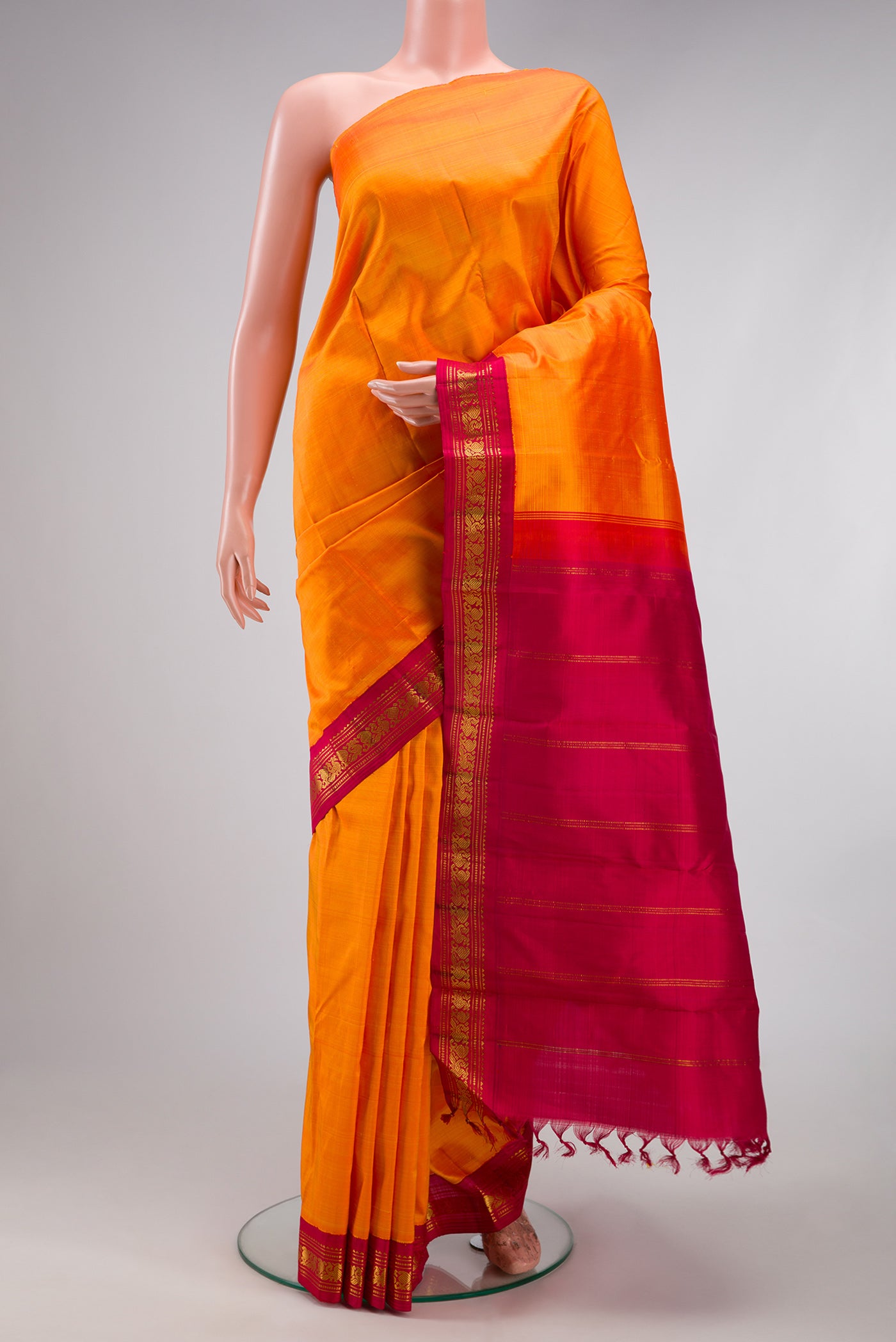 Pure Silk Pure Zari Orange Kanjivaram Saree with Plain Body and One Side Border.  displayed on a mannequin