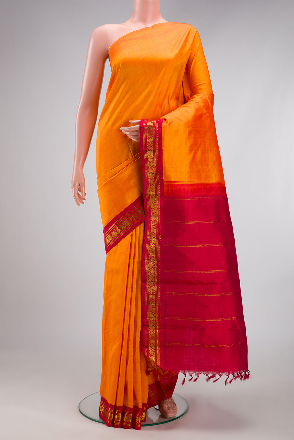 Pure Silk Pure Zari Orange Kanjivaram Saree with Plain Body and One Side Border.  displayed on a mannequin