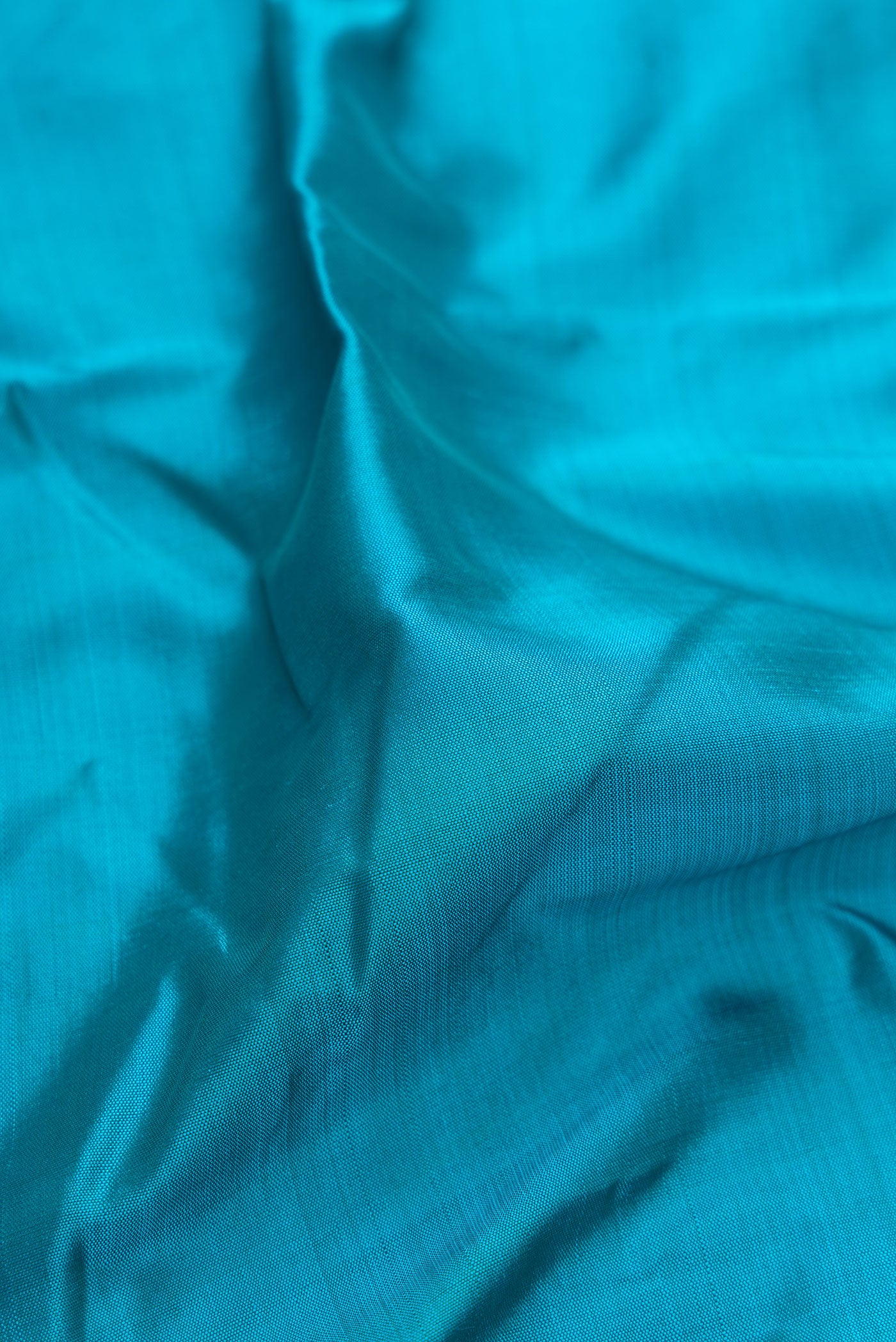 Close up of Pure Silk Pure Zari Peacock Blue Kanjivaram Saree with Plain Body and One Side Border.  displaying folds