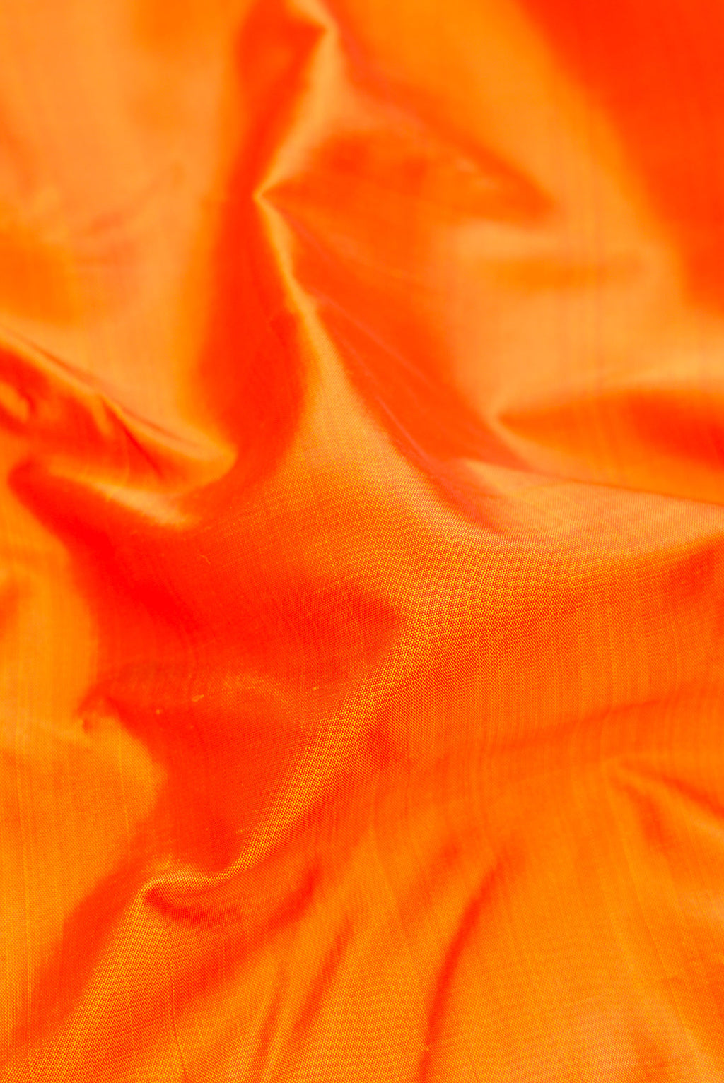 Close up of Pure Silk Pure Zari Orange Kanjivaram Saree with Plain Body and One Side Border.  displaying folds