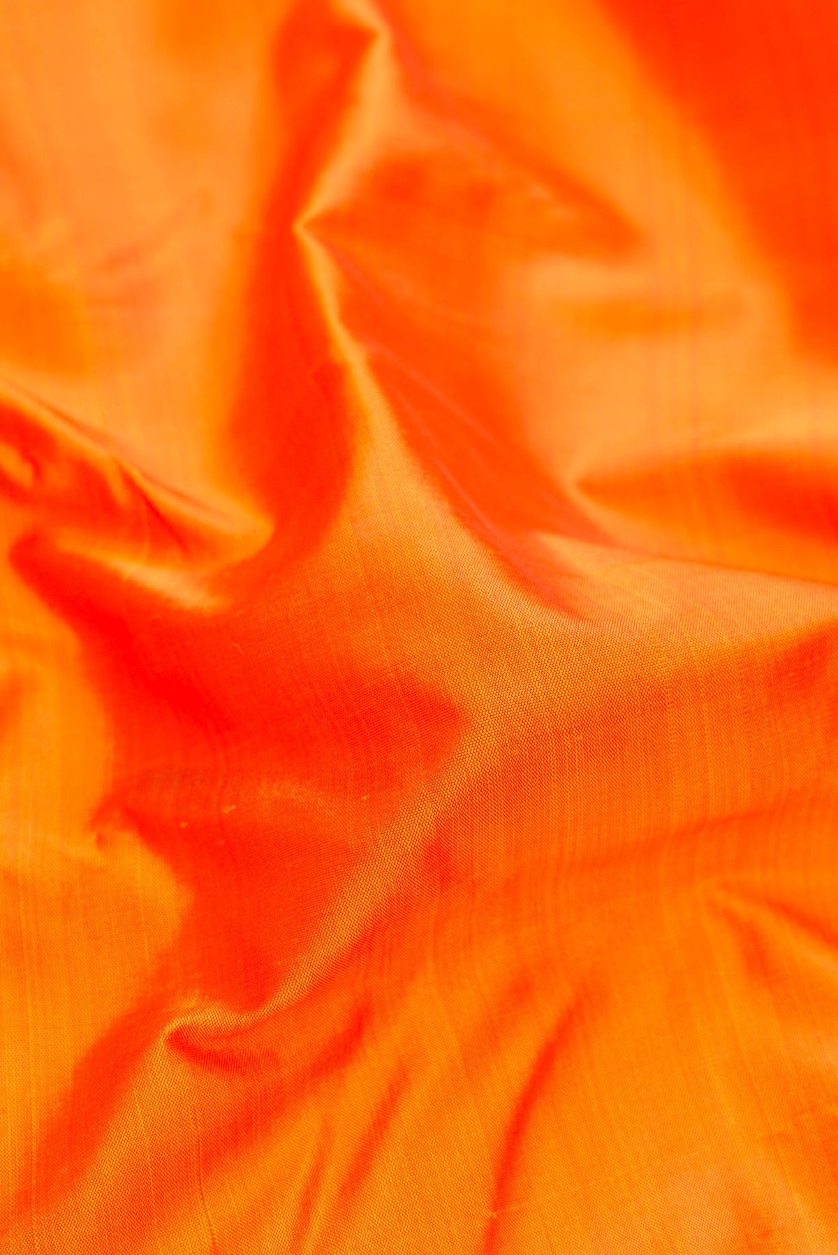 Close up of Pure Silk Pure Zari Orange Kanjivaram Saree with Plain Body and One Side Border.  displaying folds