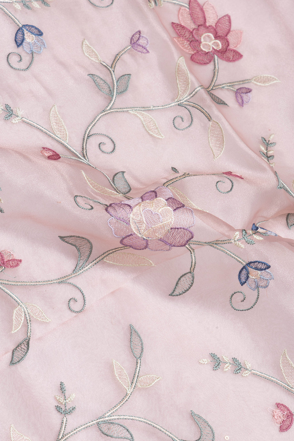 Close up of Rose Gold Organza Silk Saree with Embroidery on the body and Embroidery Border.  displaying folds
