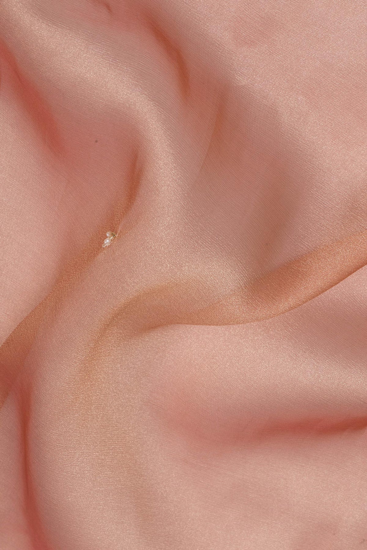Close up of Peach Dual Tone Organza Saree with Embroidery on the body and Sequin Border.  displaying folds