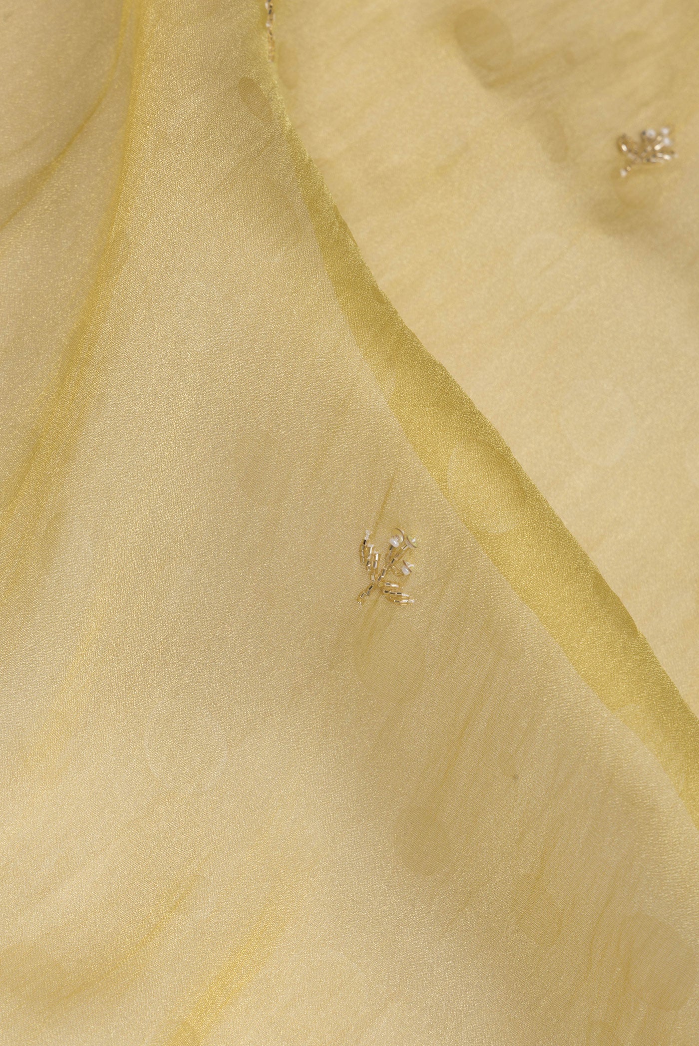 Close up of Gold Organza Silk Saree with Embroidery on the body and Sequin Border.  displaying folds