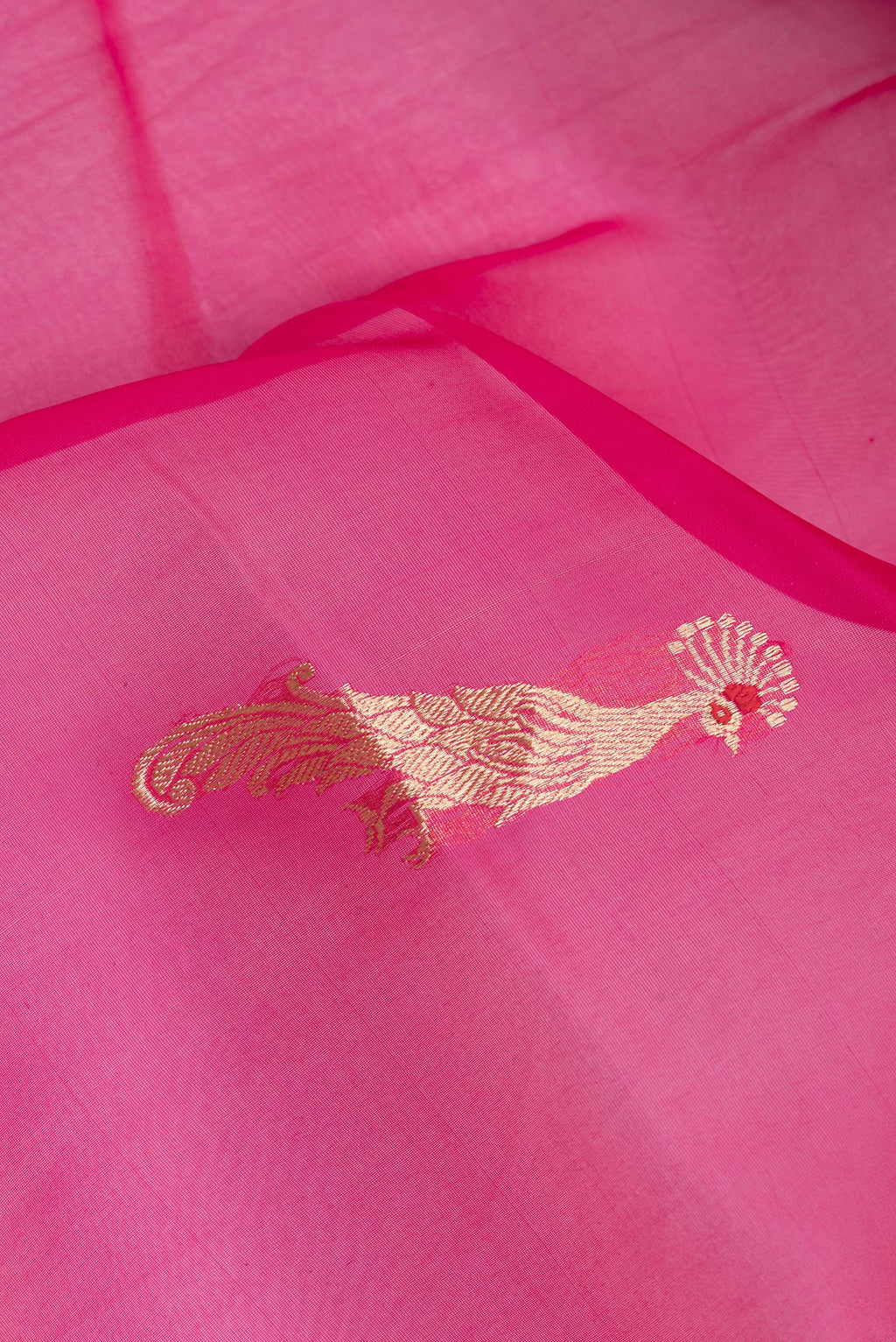 Close up of Pink Organza Silk Saree with Zari Butta on the body and Zari Border.  displaying folds