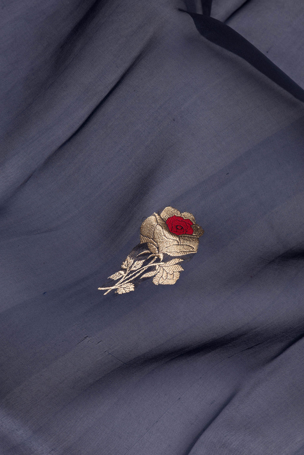 Close up of Navy Blue Organza Silk Saree with Zari And Thread Butta on the body and Zari Border.  displaying folds