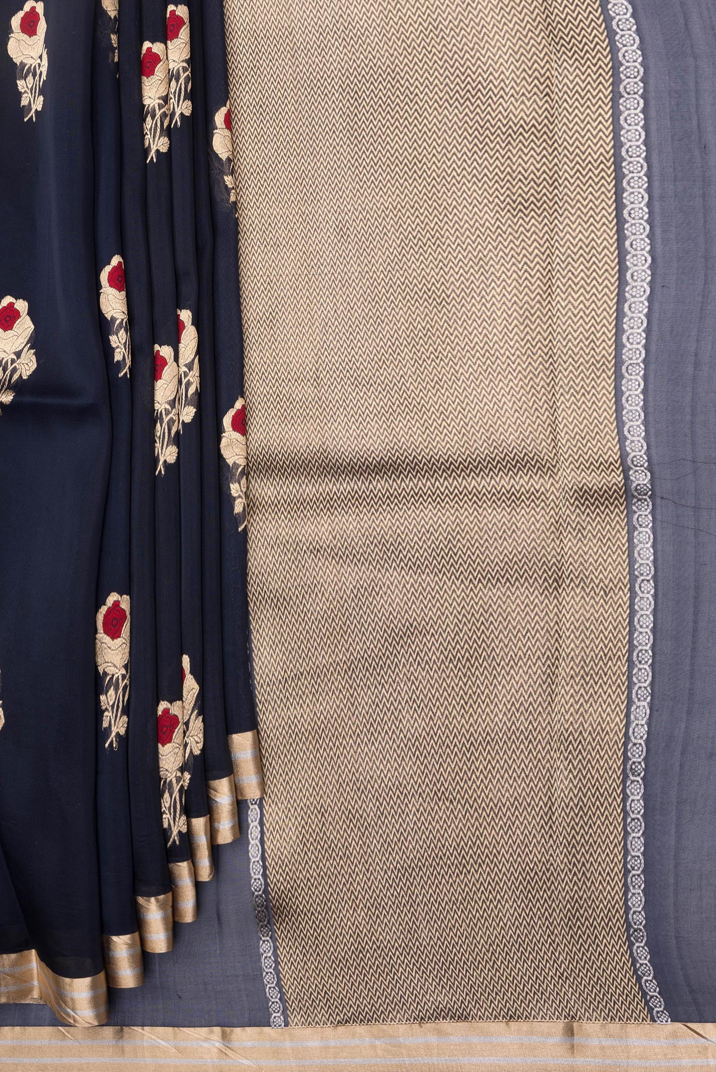 Pleats and pallu of Navy Blue Organza Silk Saree with Zari And Thread Butta on the body and Zari Border. 
