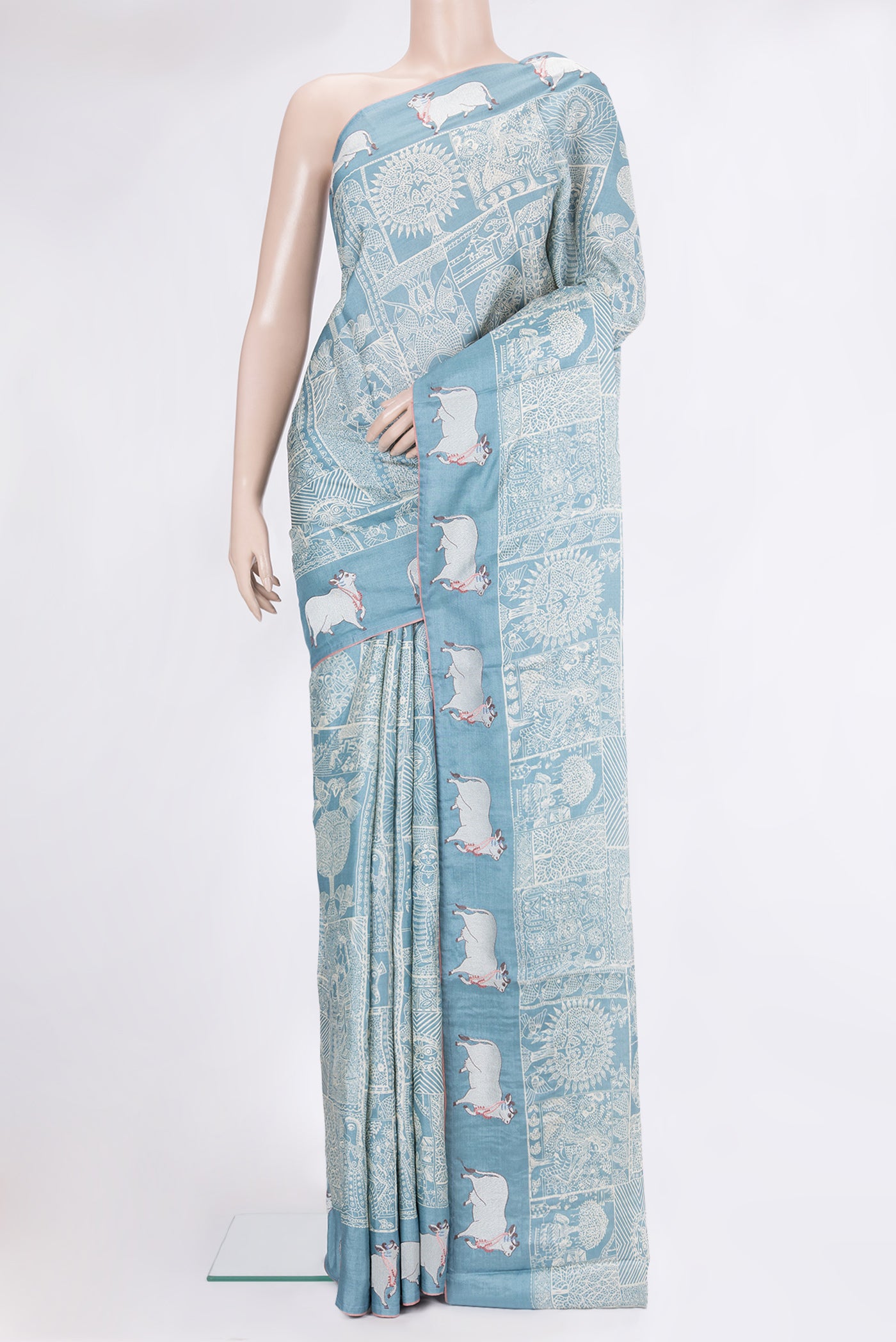 Light Blue Tussar Silk Saree with Printed design on the body and Embroidery Border.  displayed on a mannequin