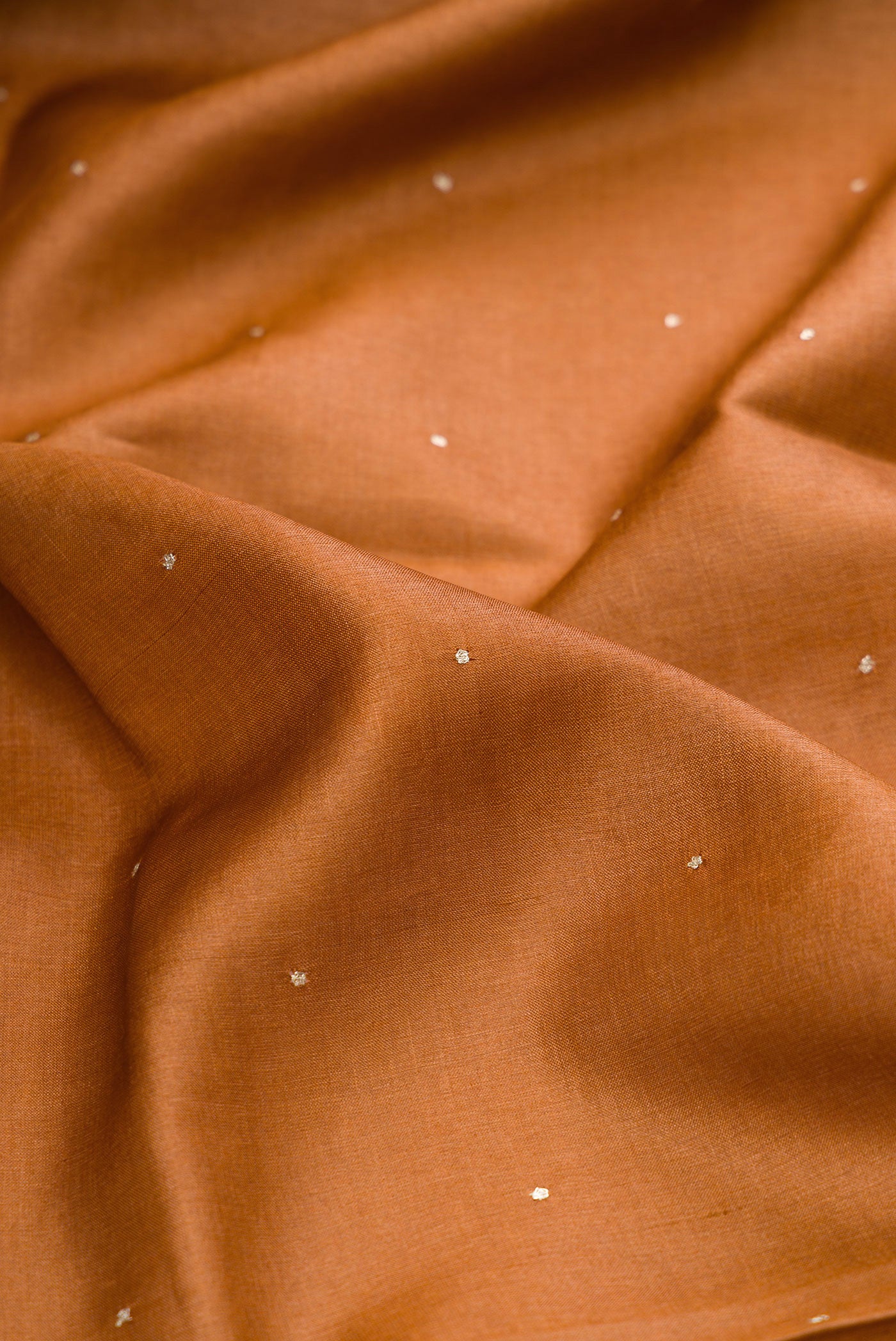 Close up of Brick Orange Dual Tone Tussar Silk Saree with Embroidery on the body and Embroidery Border.  displaying folds