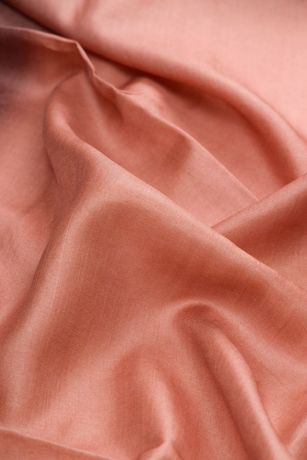 Close up of Rose Gold Tussar Silk Saree with Plain Body and Embroidery Border.  displaying folds