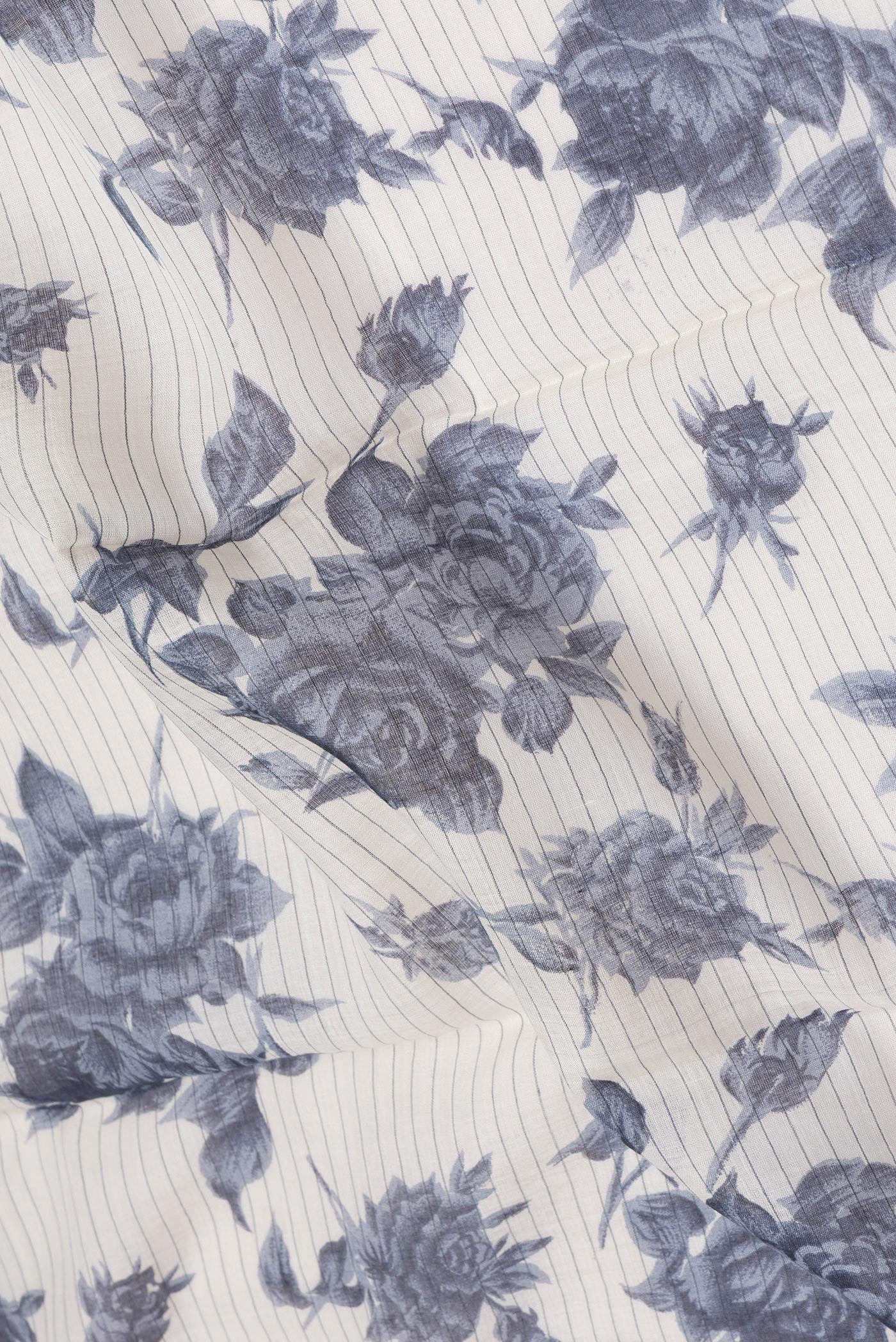 Close up of Cream Tussar Silk Saree with Floral Print on the body and Zari And Thread Border.  displaying folds