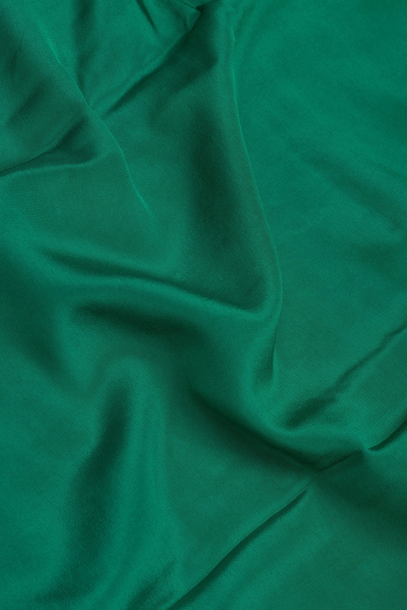Close up of Green Crepe Saree with Plain Body and Zari Border.  displaying folds