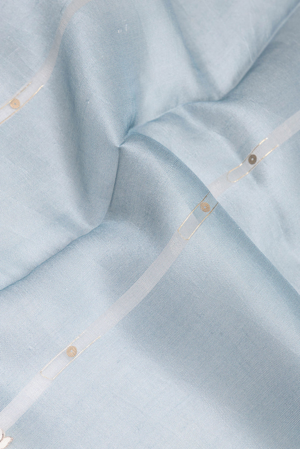Close up of Pure Silk Light Blue Tussar Saree with Floral Print on the body and Zari Border.  displaying folds