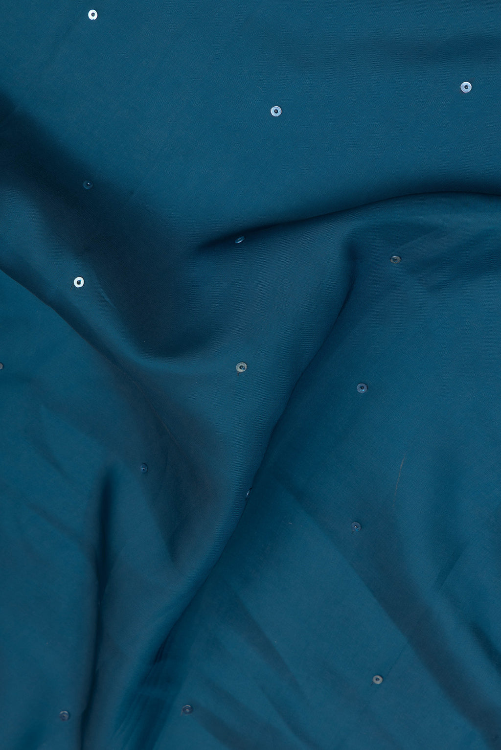 Close up of Peacock Blue Blended Satin Crepe Saree with Embroidery on the body and Embroidery Border.  displaying folds