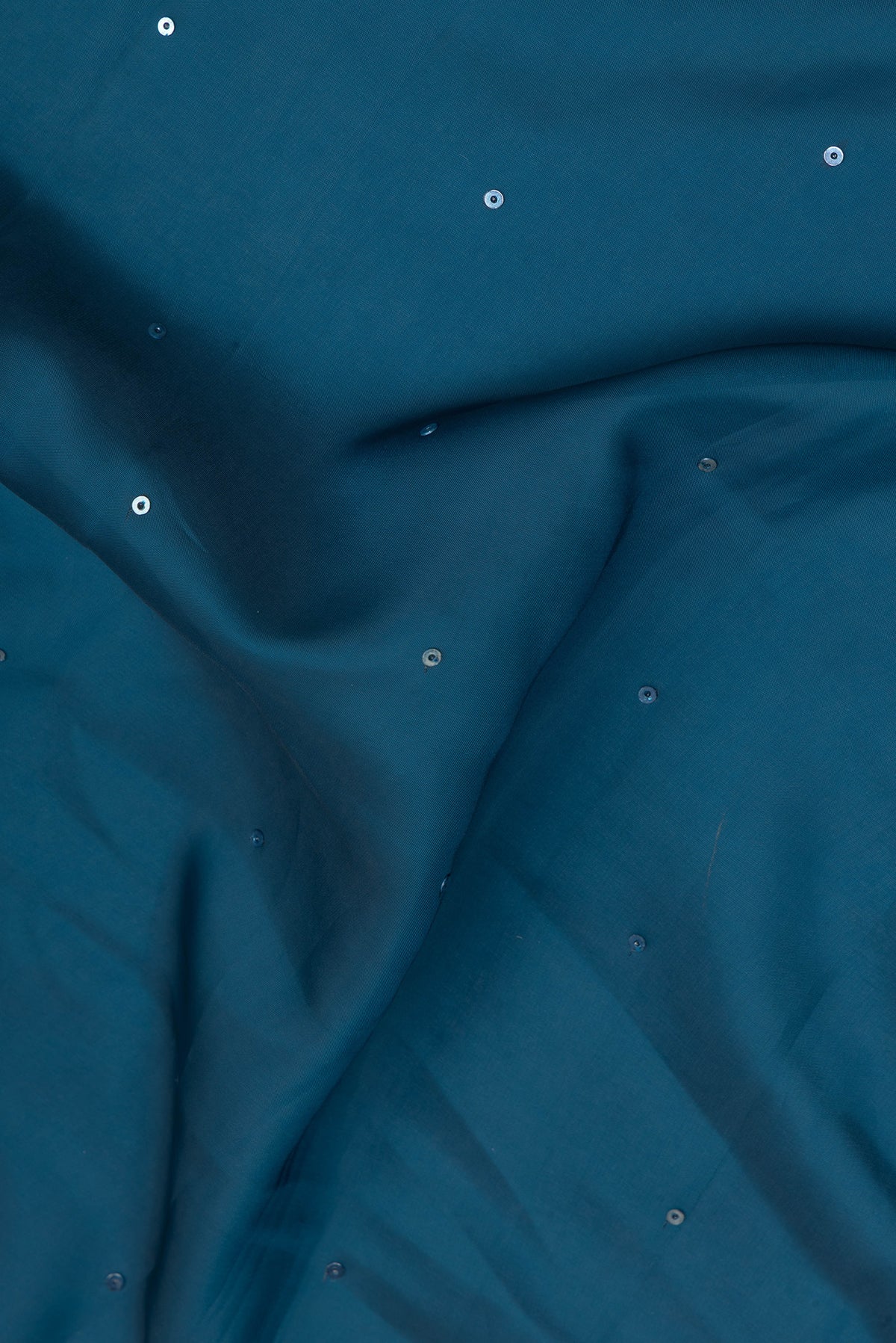 Close up of Peacock Blue Blended Satin Crepe Saree with Embroidery on the body and Embroidery Border.  displaying folds