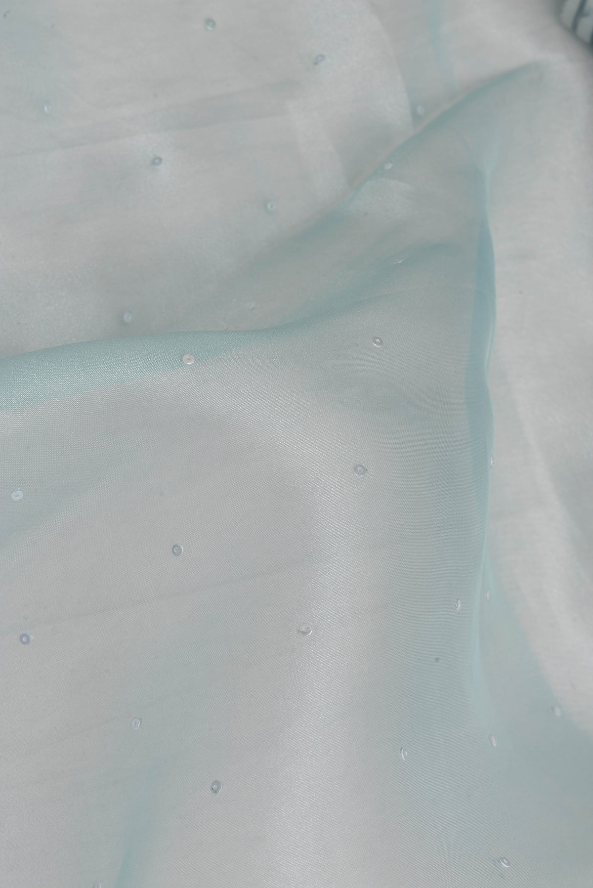 Close up of Sky Blue Dual Tone Organza Saree with Embroidery on the body and Embroidery Border.  displaying folds