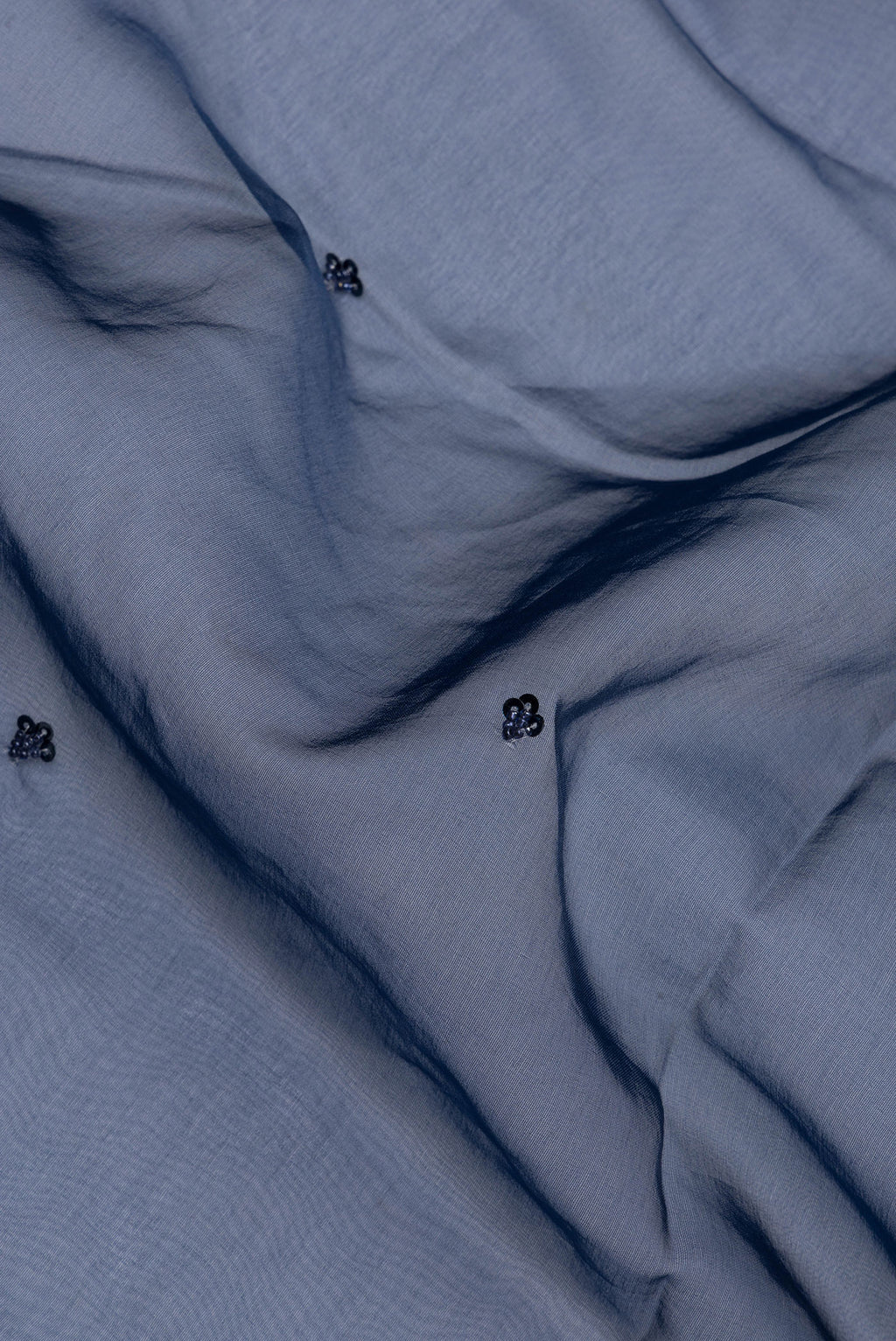 Close up of Pure Silk Navy Blue Dual Tone Organza Saree with Embroidery on the body and Sequin Border.  displaying folds