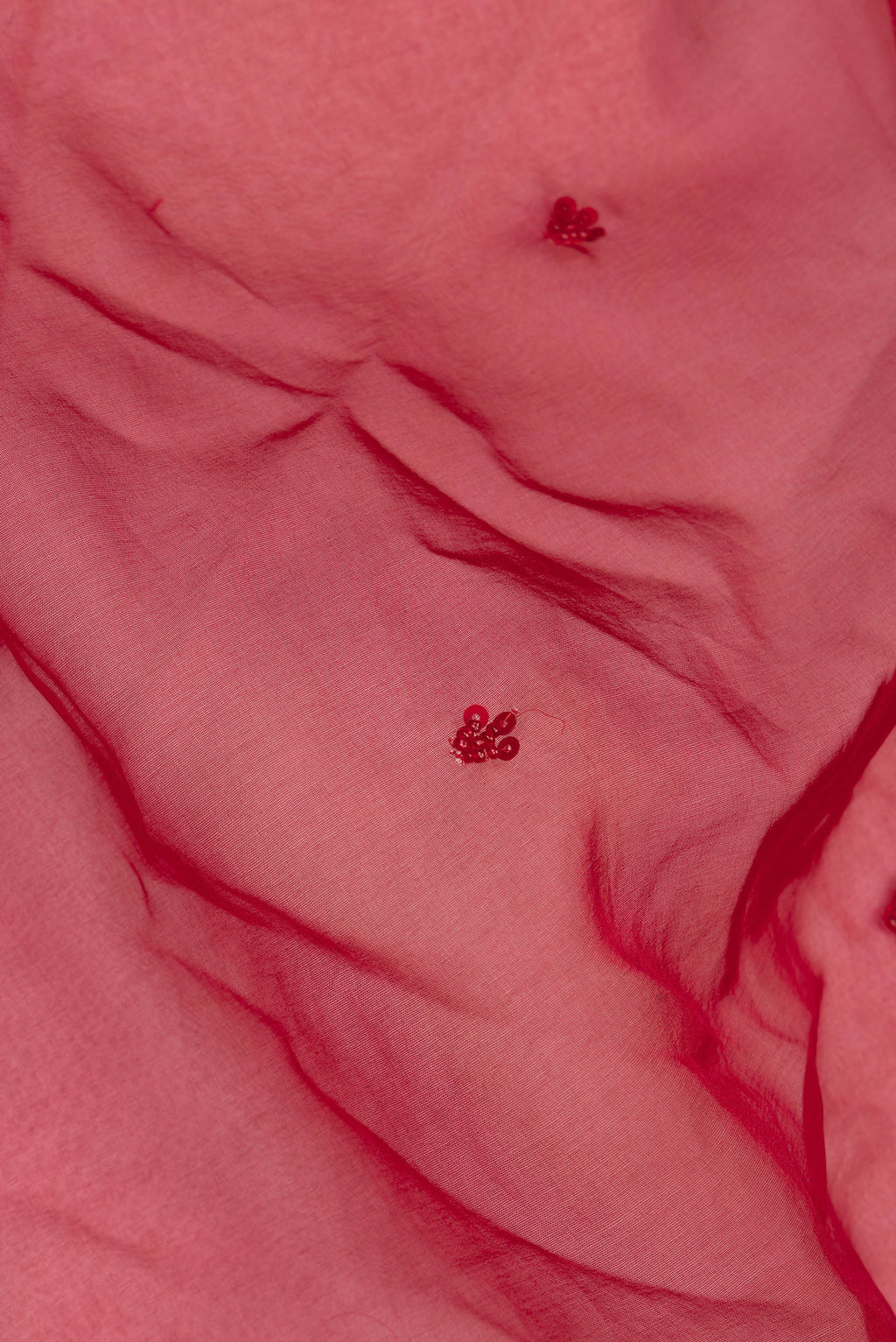 Close up of Red Organza Saree with Embroidered on the body and Sequin Border.  displaying folds
