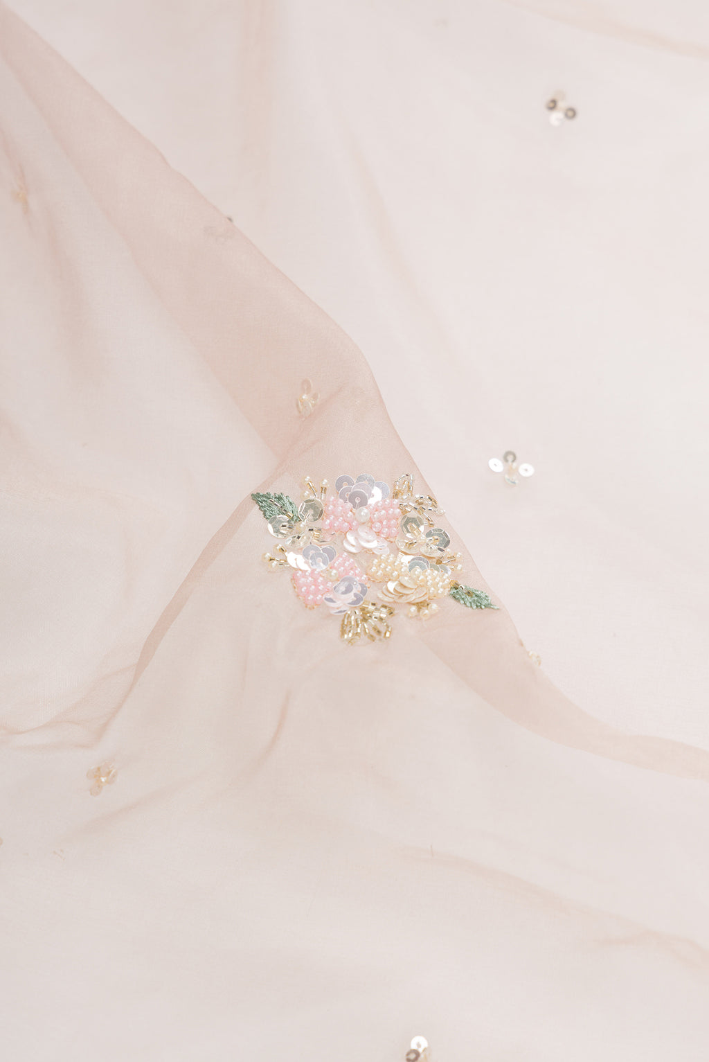 Close up of Rose Gold Organza Saree with Embroidered on the body and Sequin Border.  displaying folds