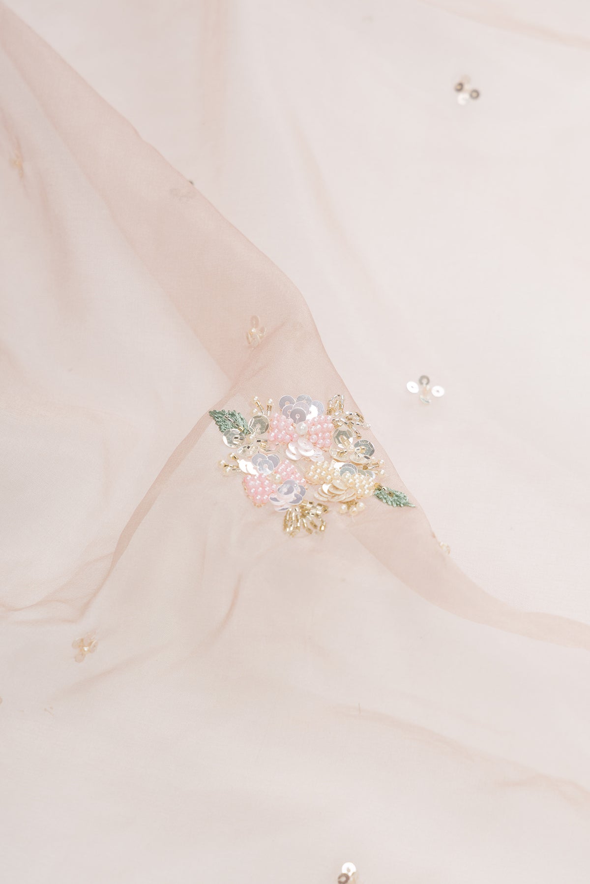 Close up of Rose Gold Organza Saree with Embroidered on the body and Sequin Border.  displaying folds