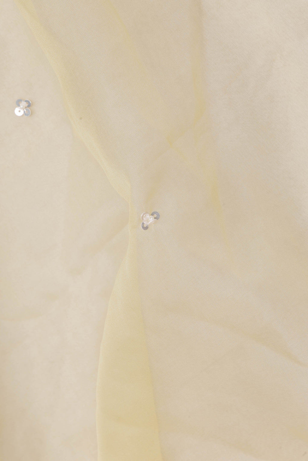 Close up of Lemon Yellow Organza Saree with Embroidered on the body and Sequin Border.  displaying folds