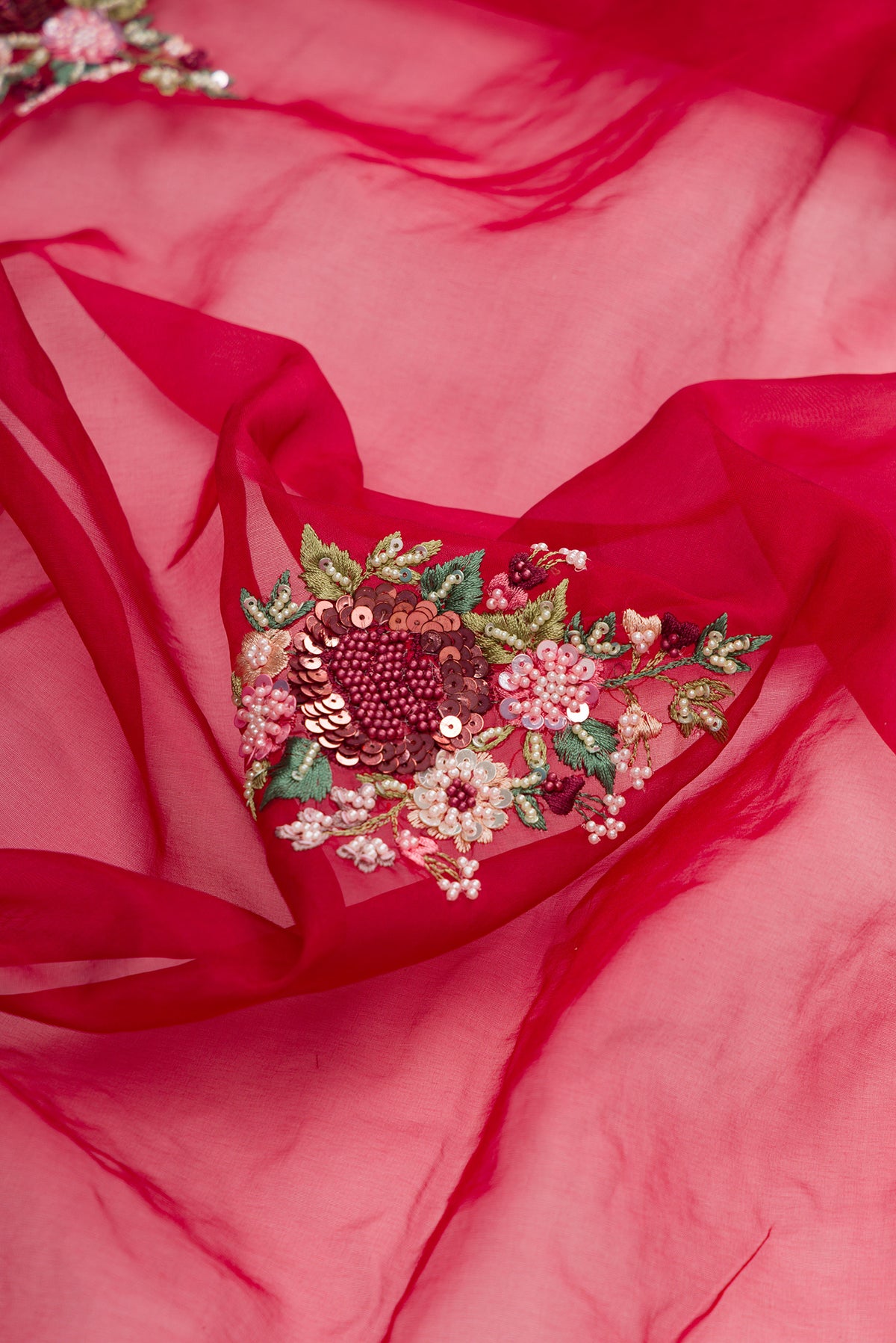 Close up of Red Organza Saree with Embroidered on the body and Sequin Border.  displaying folds