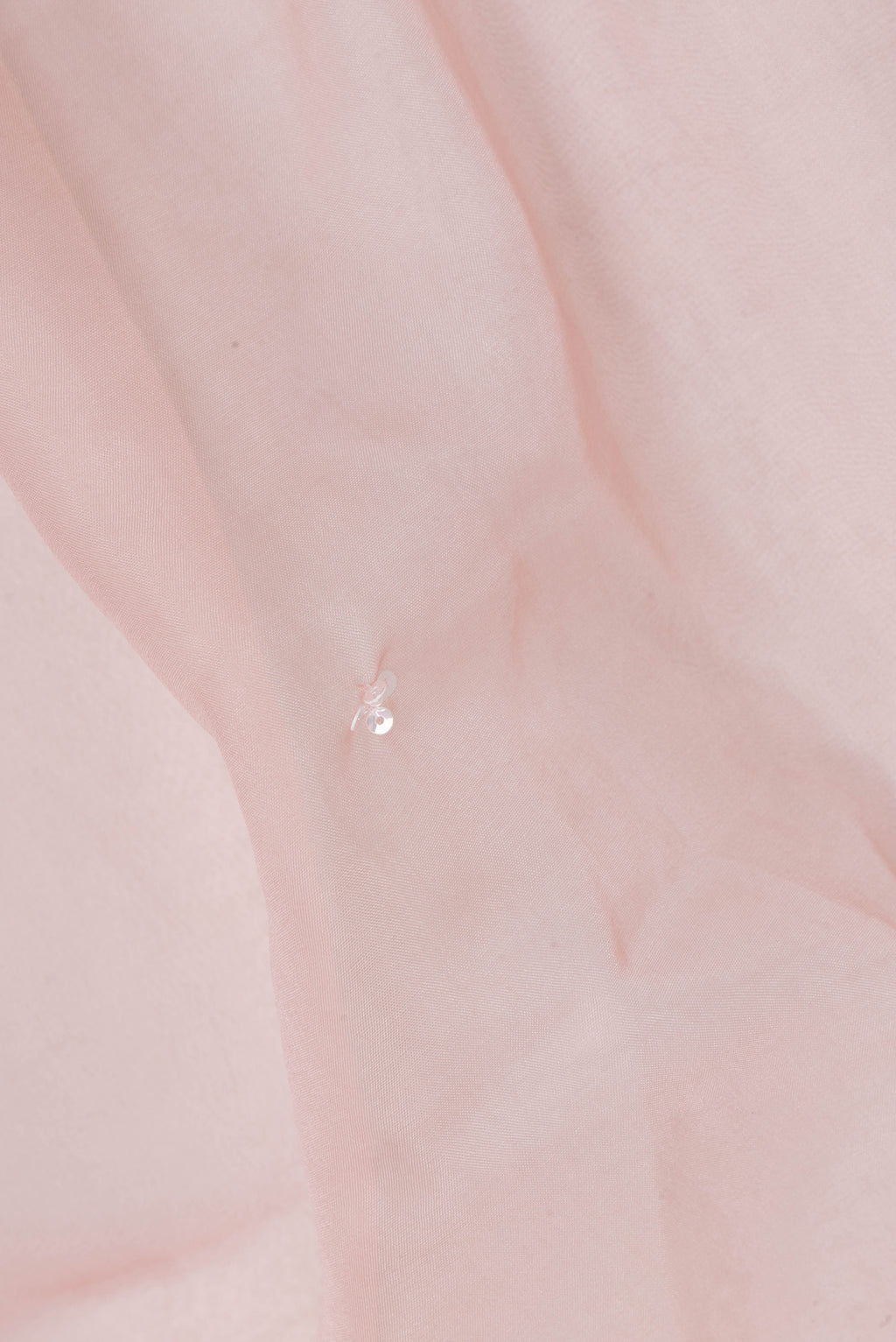 Close up of Peach Organza Saree with Embroidered on the body and Sequin Border.  displaying folds