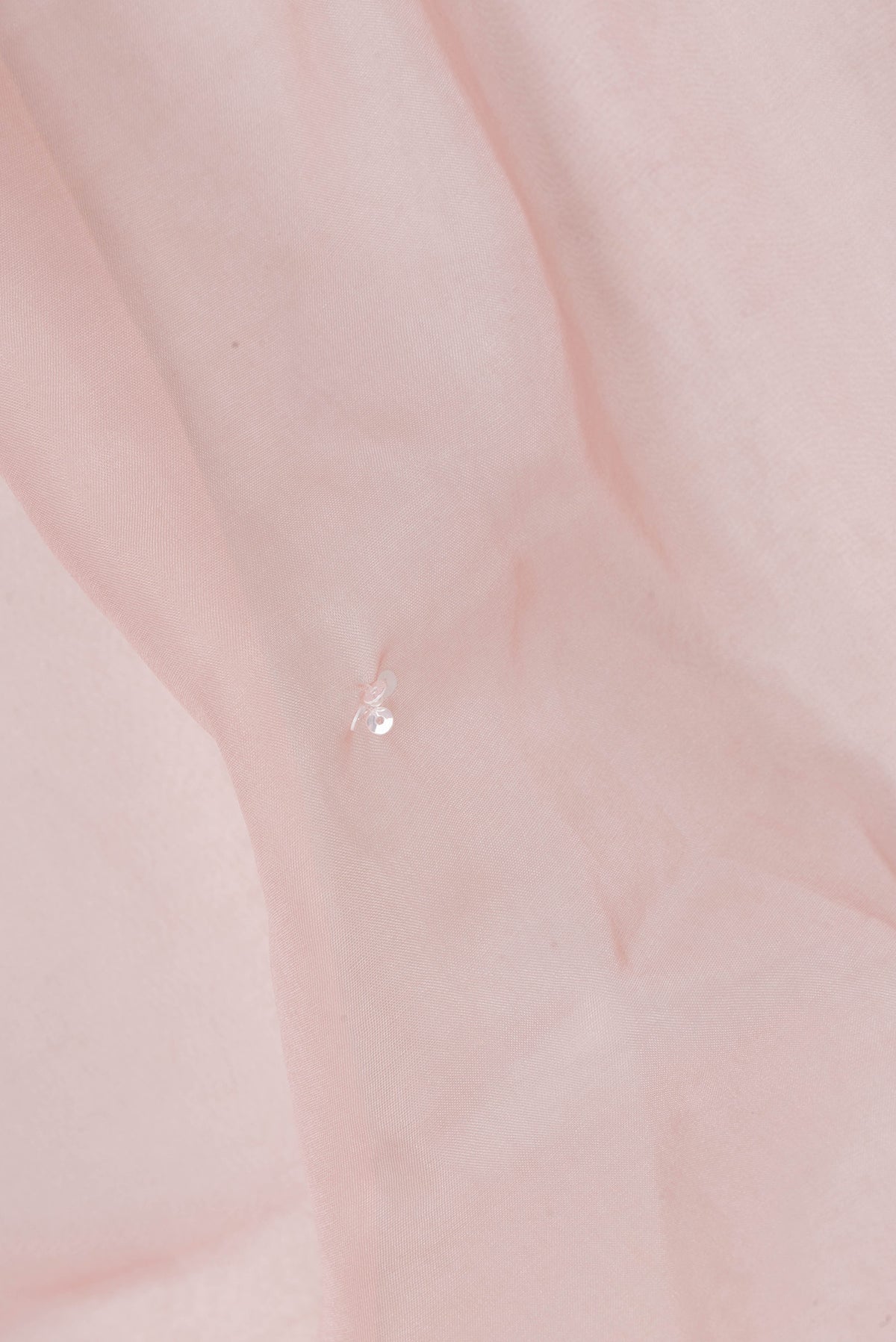 Close up of Peach Organza Saree with Embroidered on the body and Sequin Border.  displaying folds
