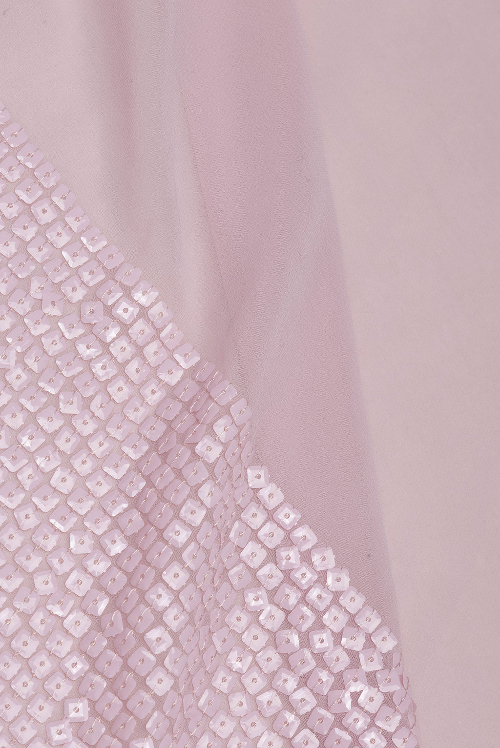 Close up of Rose Gold Georgette Saree with Embroidered on the body and Sequin Border.  displaying folds