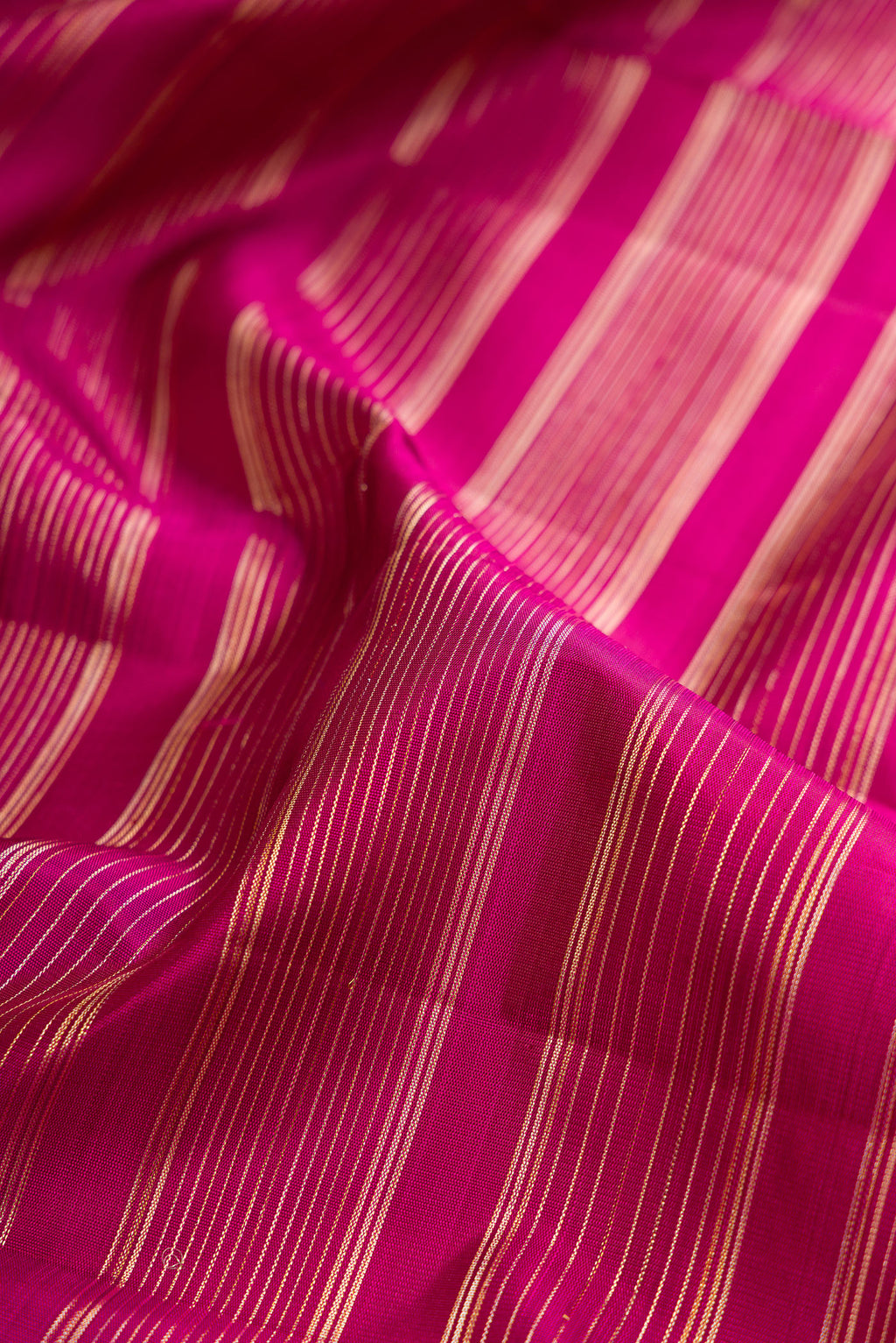 Close up of Magenta Kanchipuram Silk Saree with Stripes on the body and Fancy Border.  displaying folds