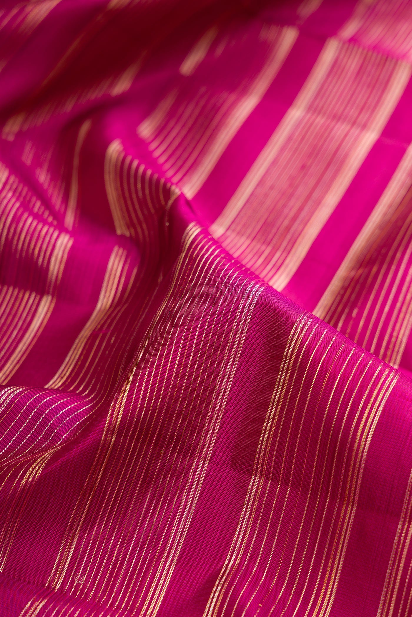 Close up of Magenta Kanchipuram Silk Saree with Stripes on the body and Fancy Border.  displaying folds