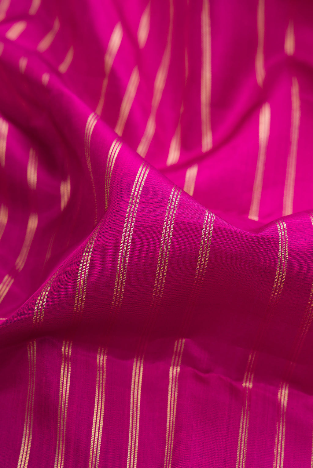 Close up of Pure Silk Rani Pink Kanchipuram Saree with Stripes on the body and Zari Border.  displaying folds