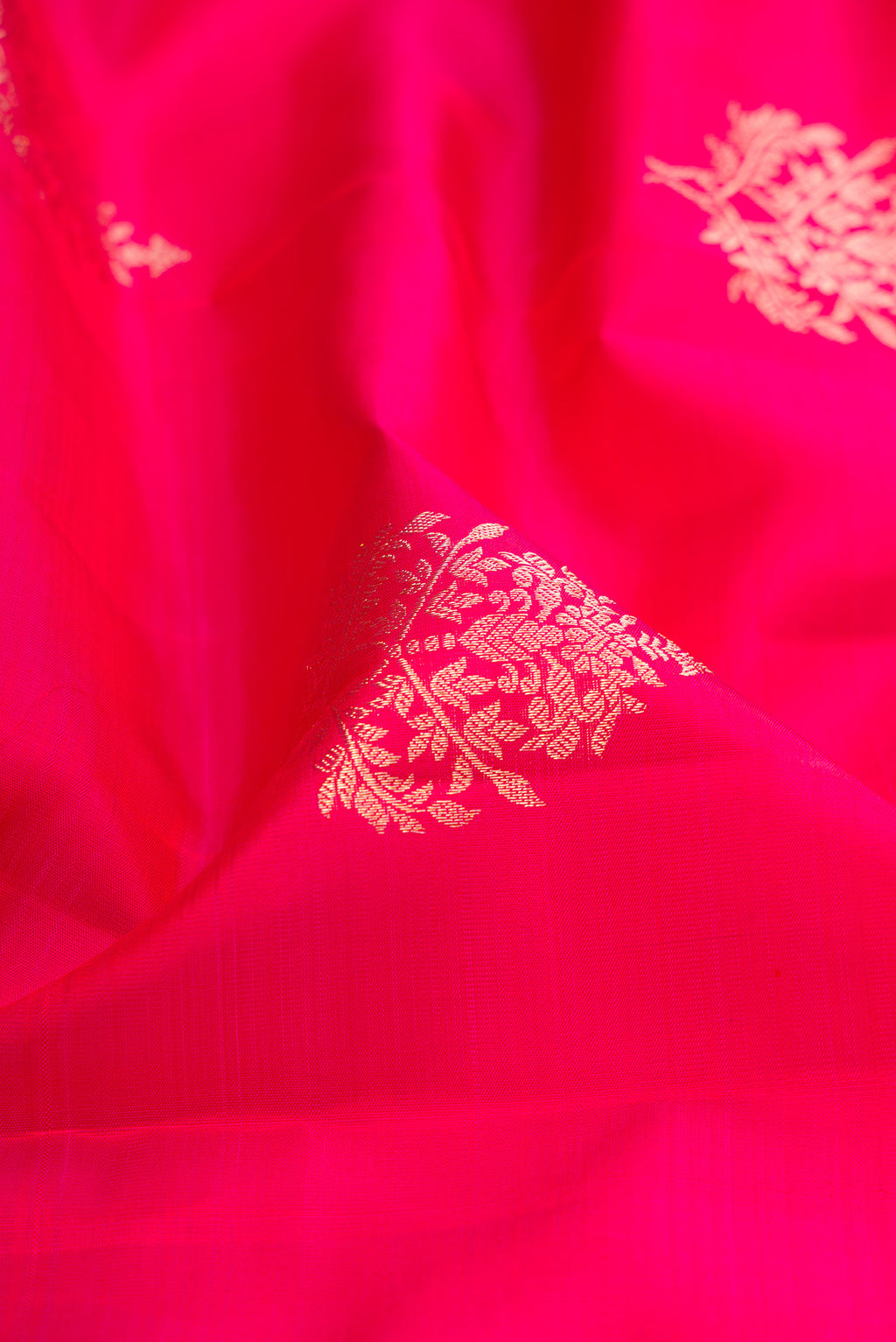 Close up of Dark Pink Kanjivaram Silk Saree with Zari Butta on the body and Zari Border.  displaying folds