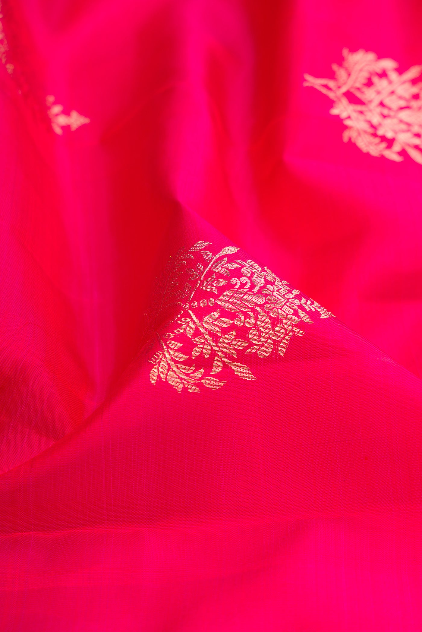 Close up of Dark Pink Kanjivaram Silk Saree with Zari Butta on the body and Zari Border.  displaying folds
