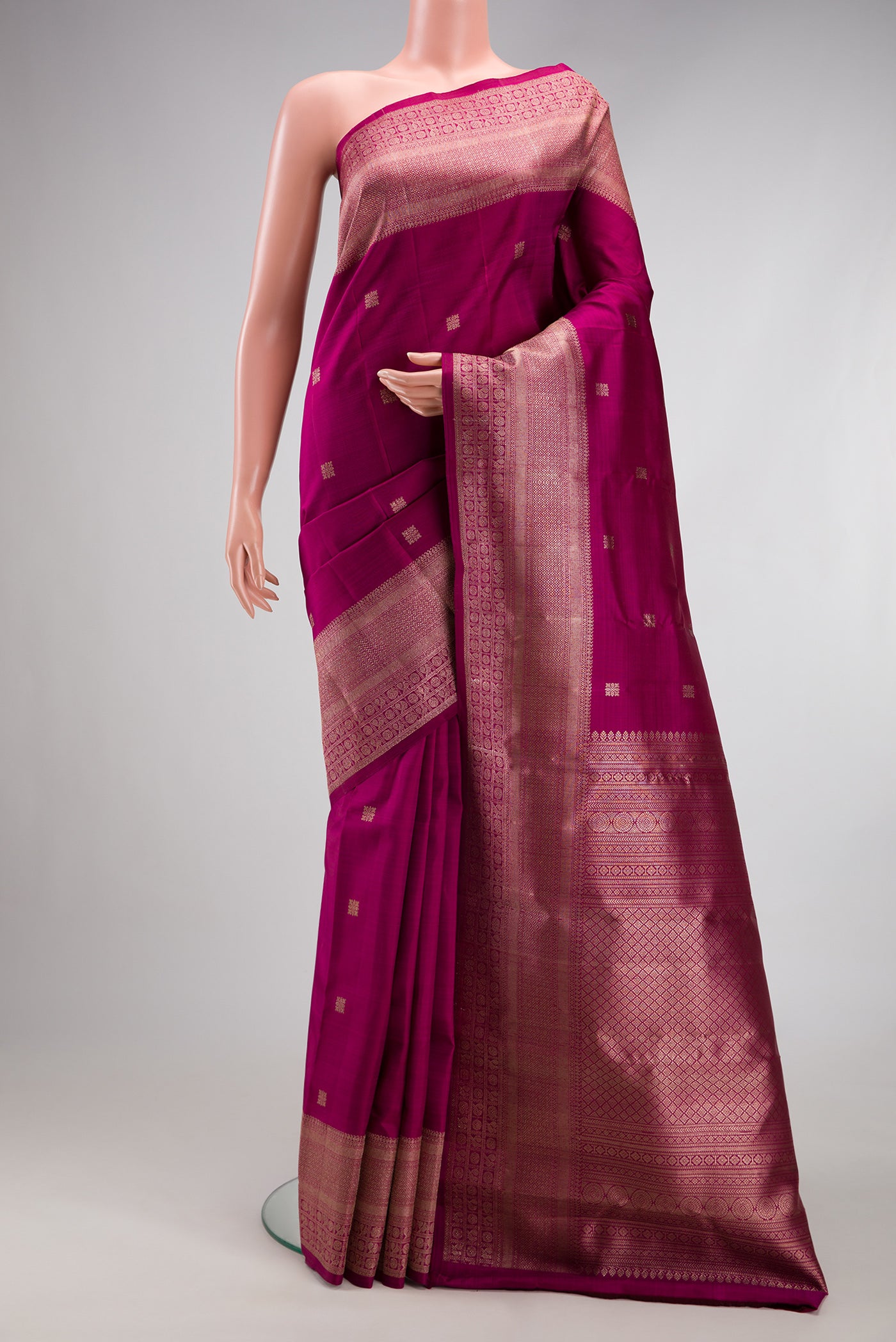 Magenta Kanjivaram Silk Saree with Zari Butta on the body and Fancy Border.  displayed on a mannequin