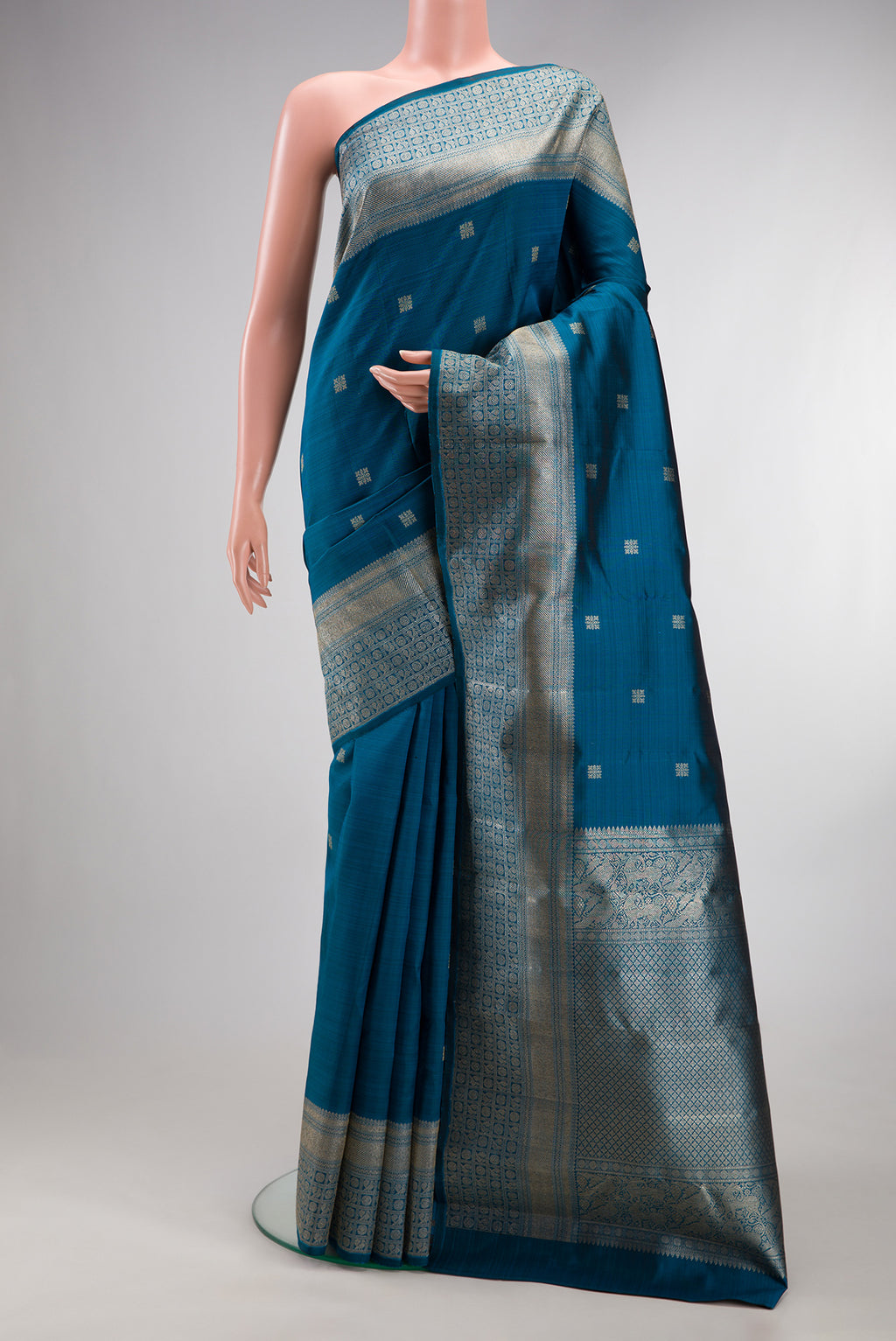 Pure Silk Peacock Blue Kanjivaram Saree with Zari Butta on the body and Fancy Border.  displayed on a mannequin