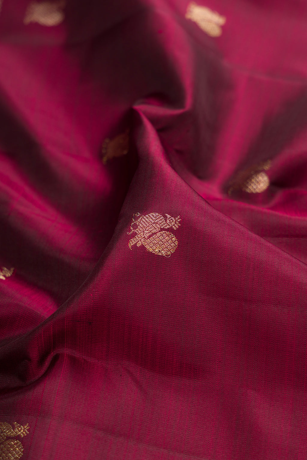 Close up of Maroon Kanjivaram Silk Saree with Zari Butta on the body and Fancy Border.  displaying folds