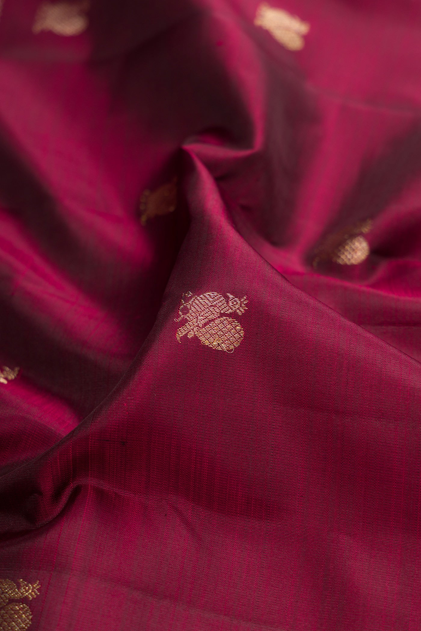 Close up of Maroon Kanjivaram Silk Saree with Zari Butta on the body and Fancy Border.  displaying folds